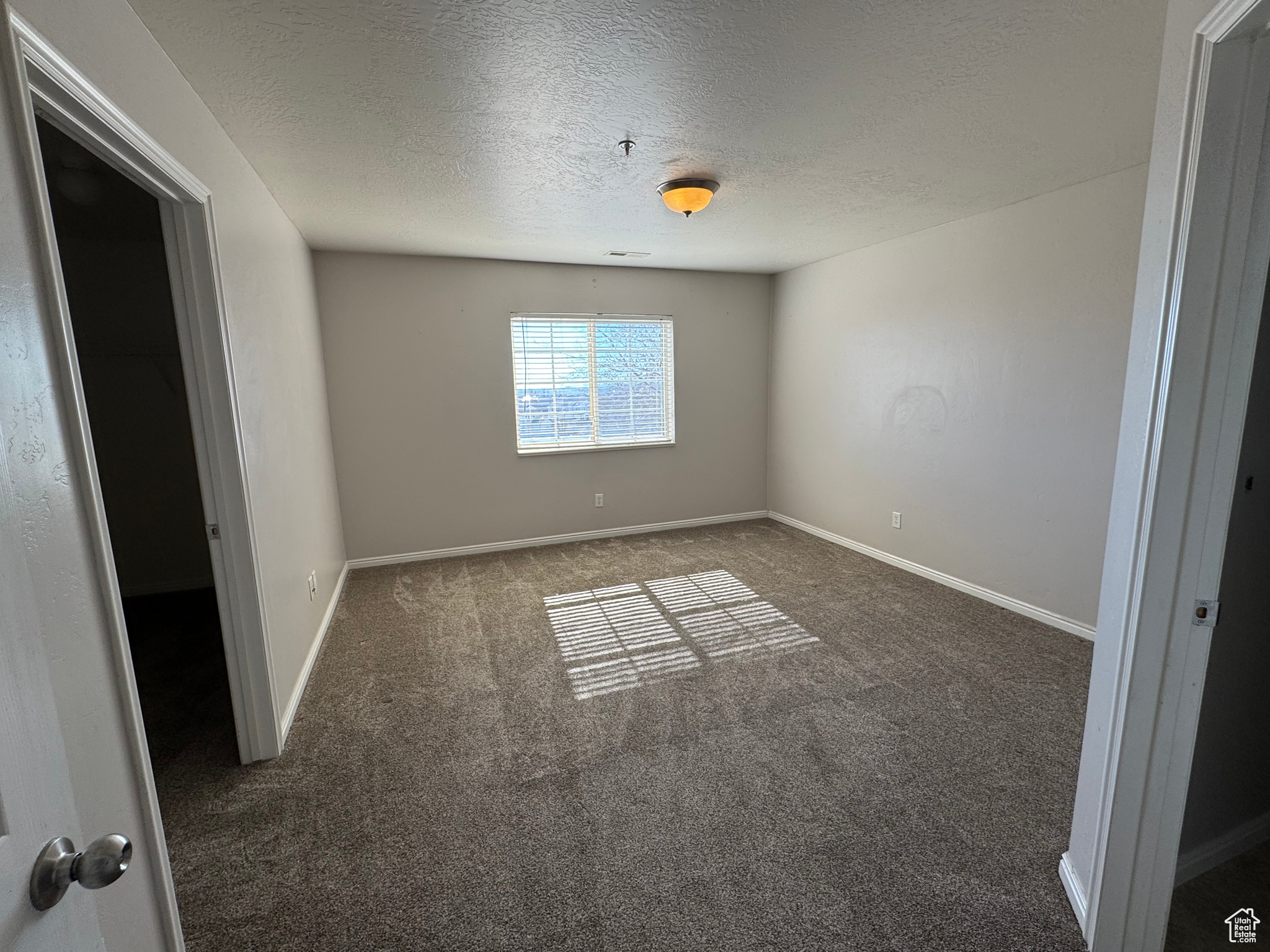 Spare room with dark carpet, a textured ceiling, and baseboards