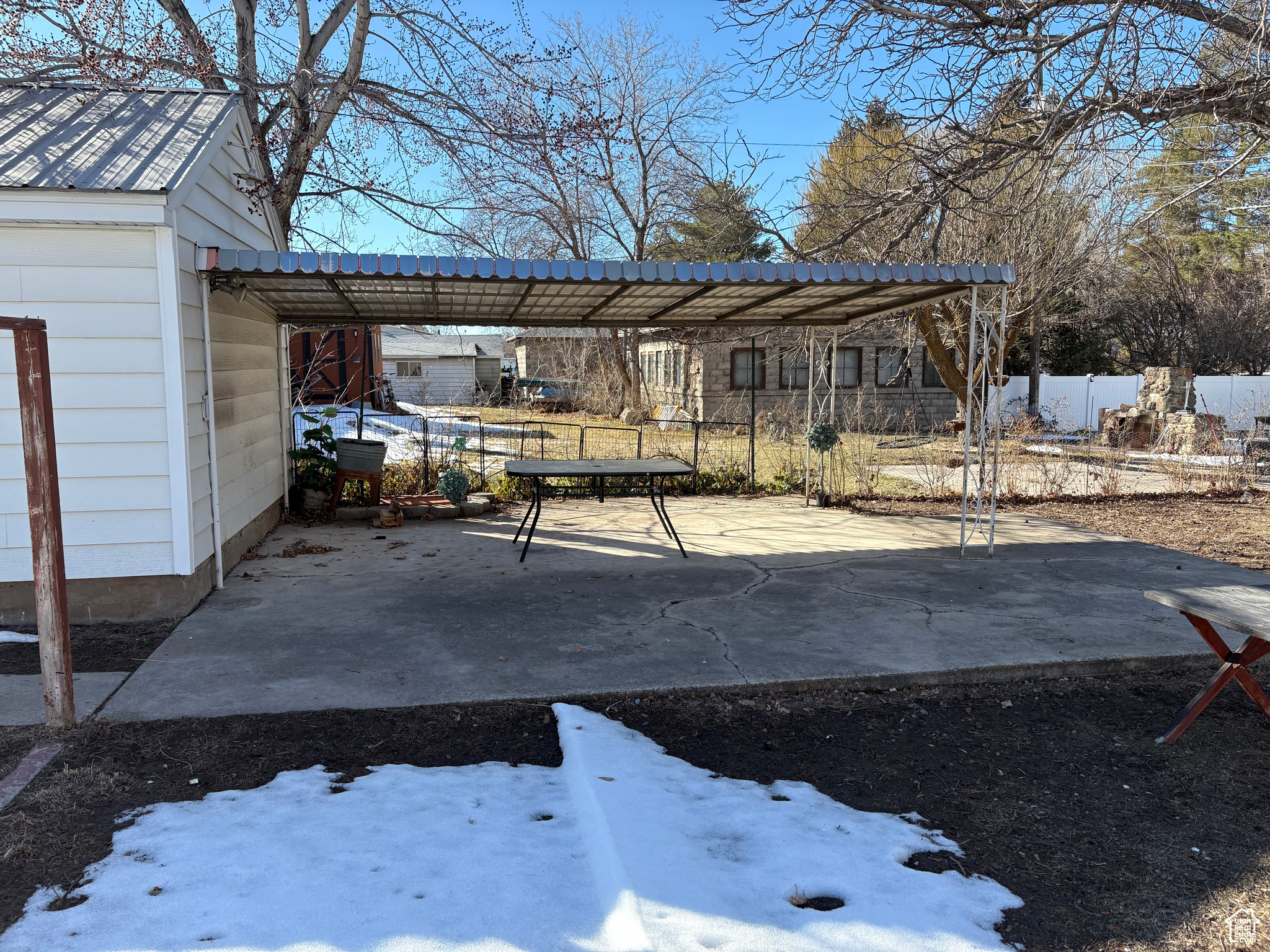 Snowy yard with a carport and fence