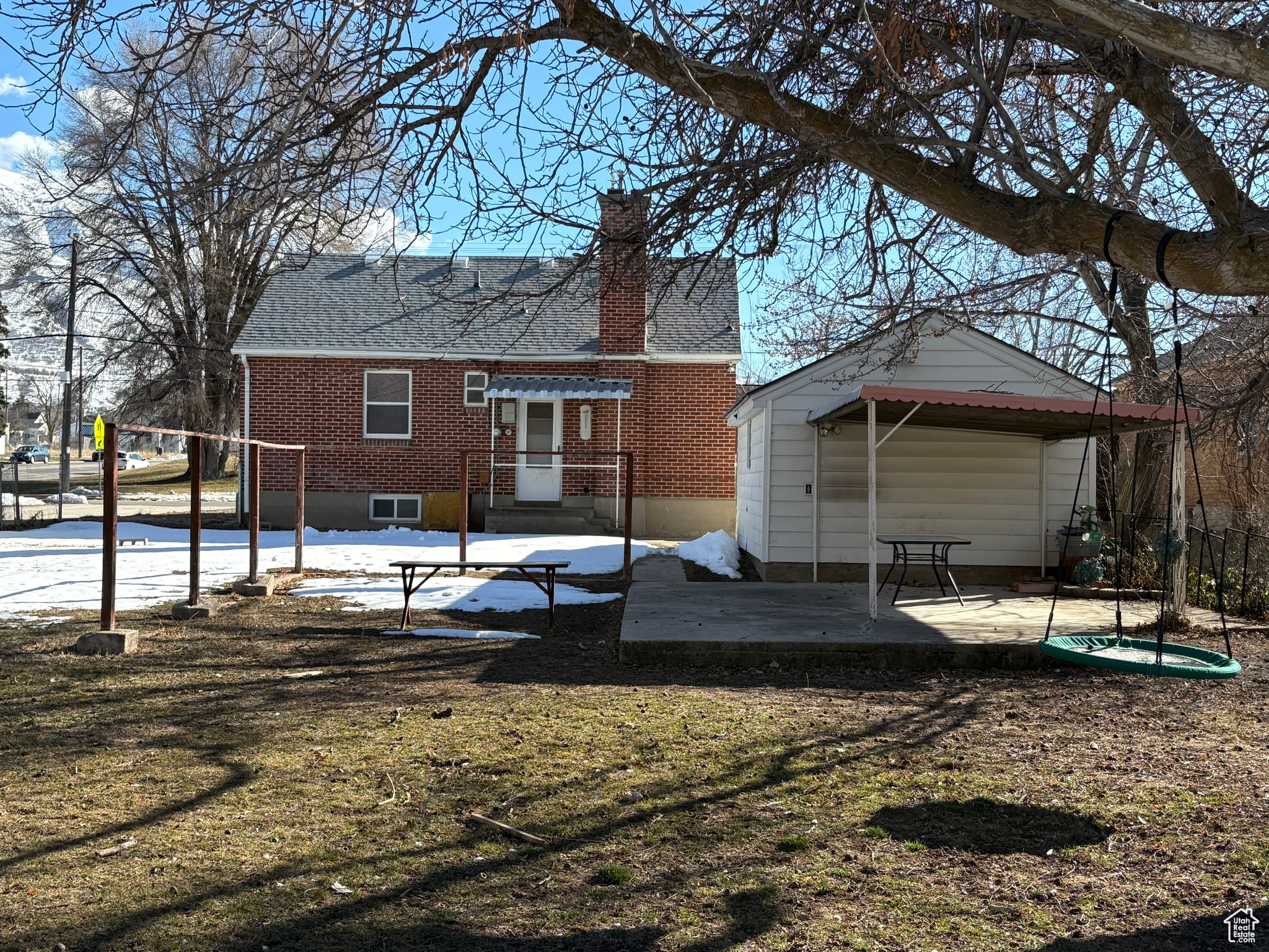 Back of property with brick siding, a chimney, a patio area, and a lawn