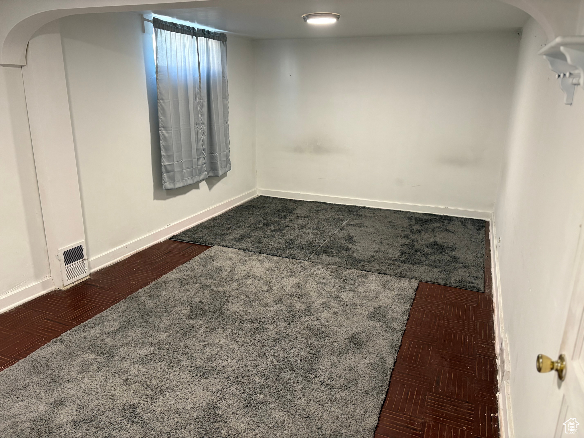 Unfurnished basement bedroom with carpet and rugs visible vents, and baseboards
