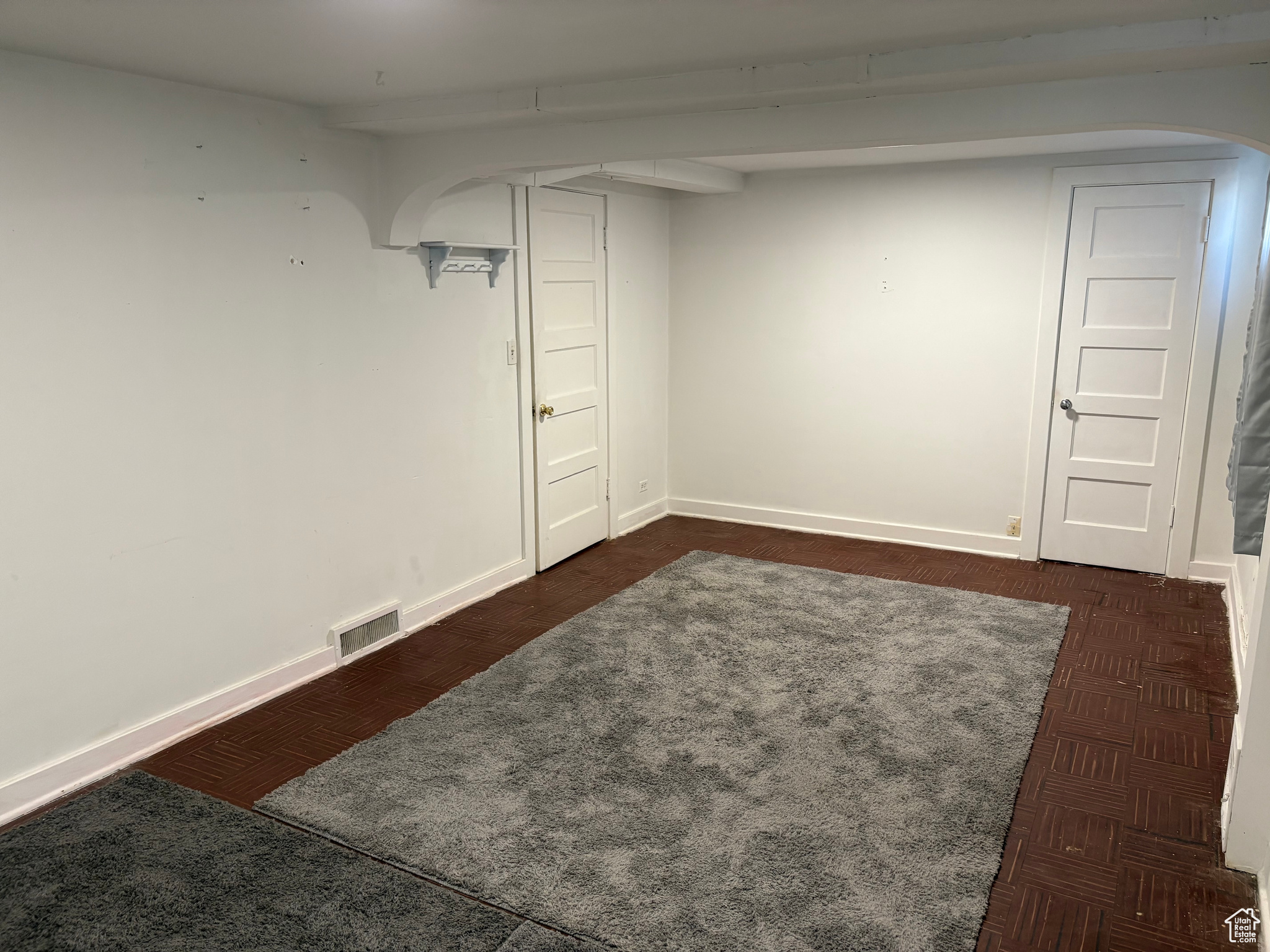 Unfurnished basement bedroom with carpet and rugs visible vents, and baseboards