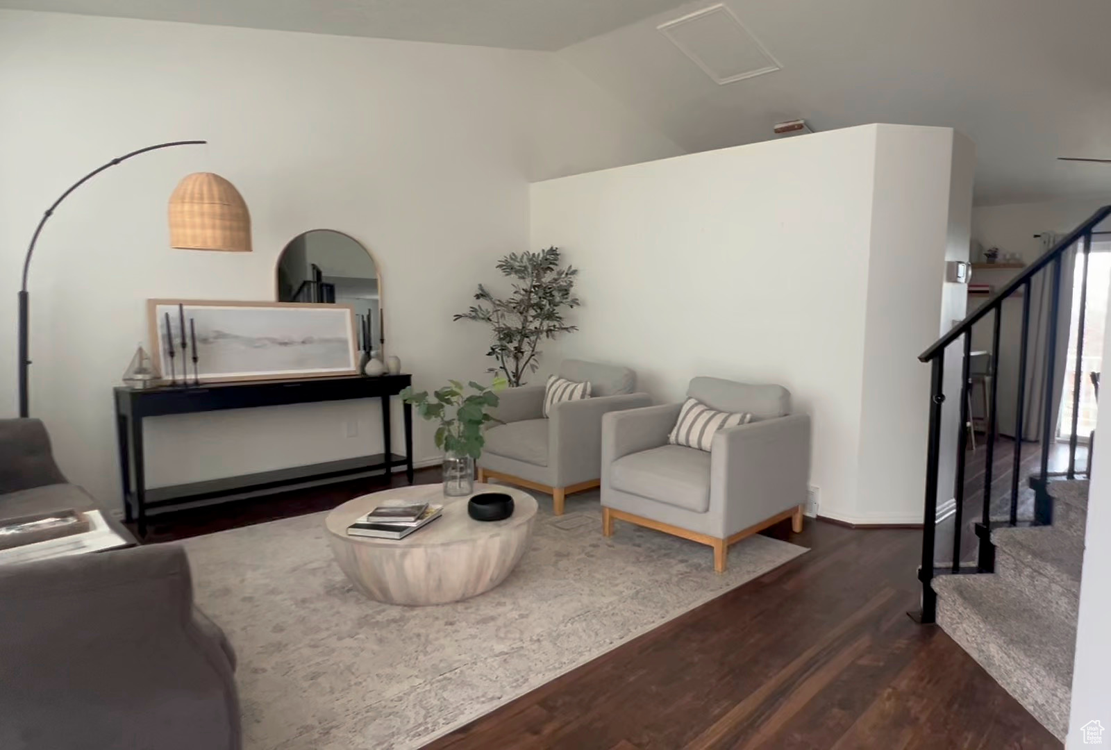 Living area with stairs, dark wood-type flooring, and vaulted ceiling