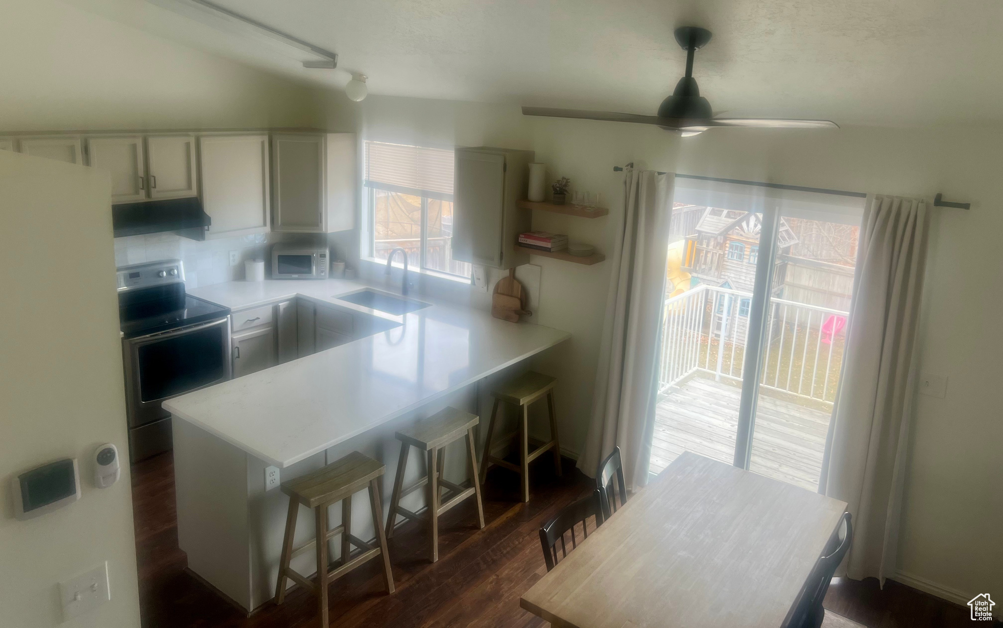 Kitchen featuring electric stove, dark wood-style flooring, light countertops, white cabinetry, and a sink