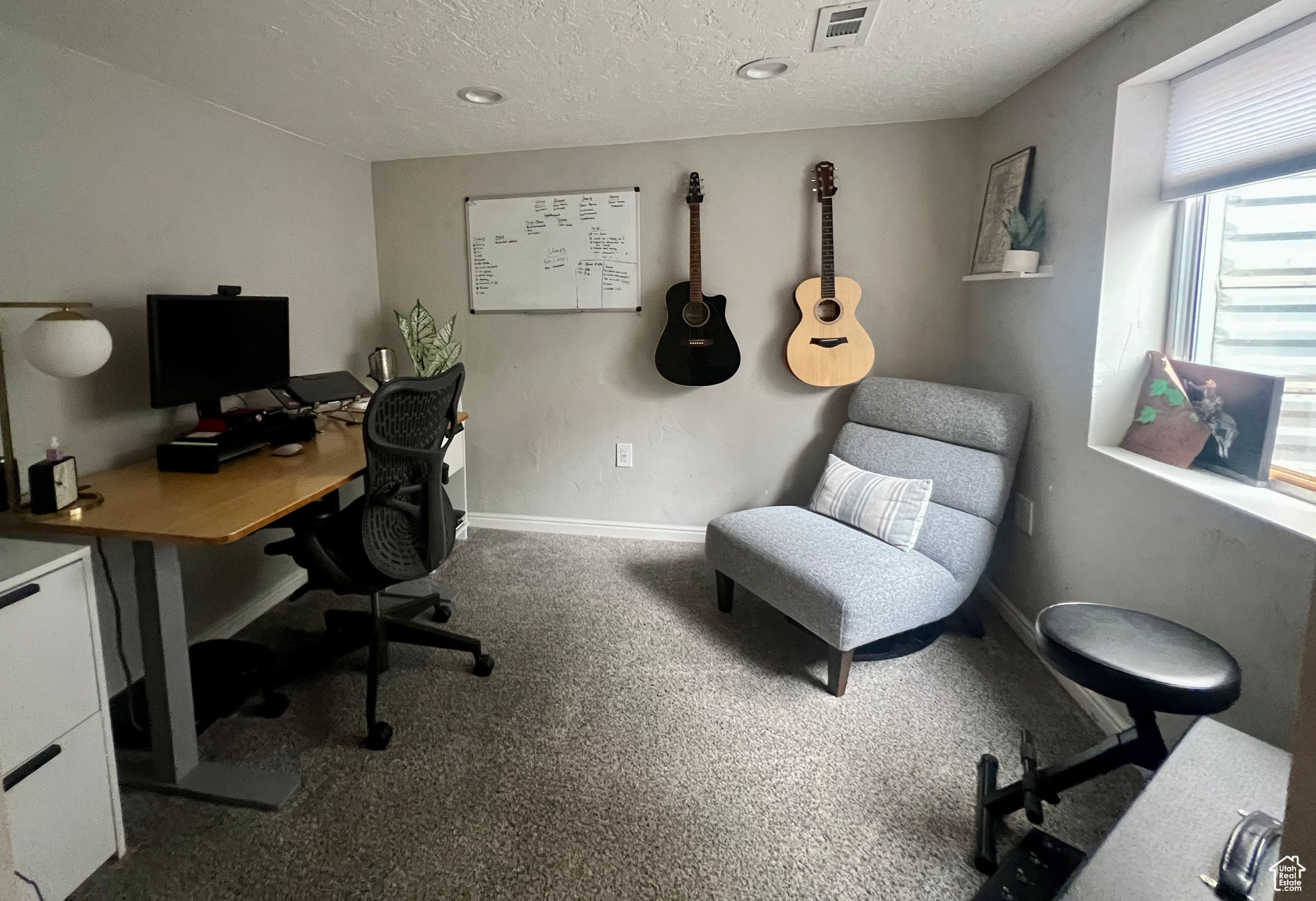 Office space featuring carpet floors, baseboards, visible vents, and a textured ceiling