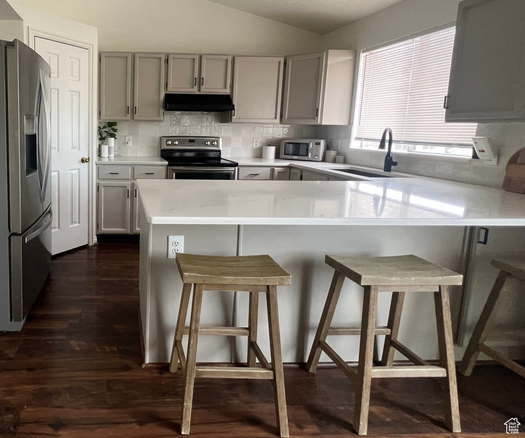 Kitchen with a peninsula, appliances with stainless steel finishes, a breakfast bar area, and light countertops