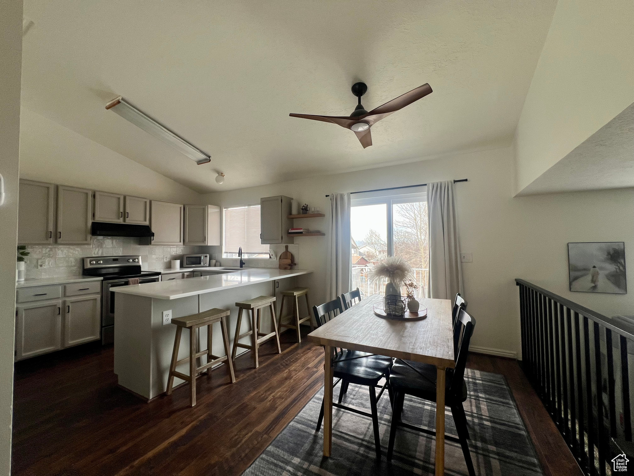 Dining area with dark wood-style floors, lofted ceiling, and ceiling fan
