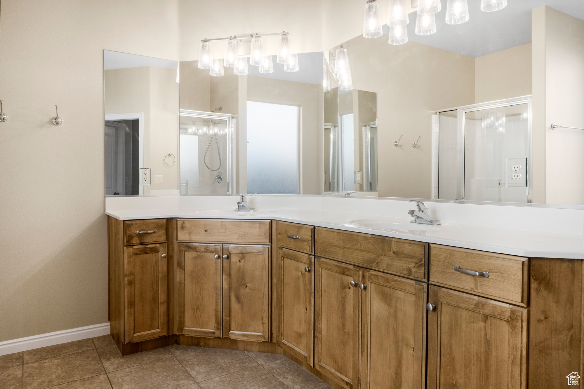 Bathroom featuring double vanity, a stall shower, a sink, and tile patterned floors