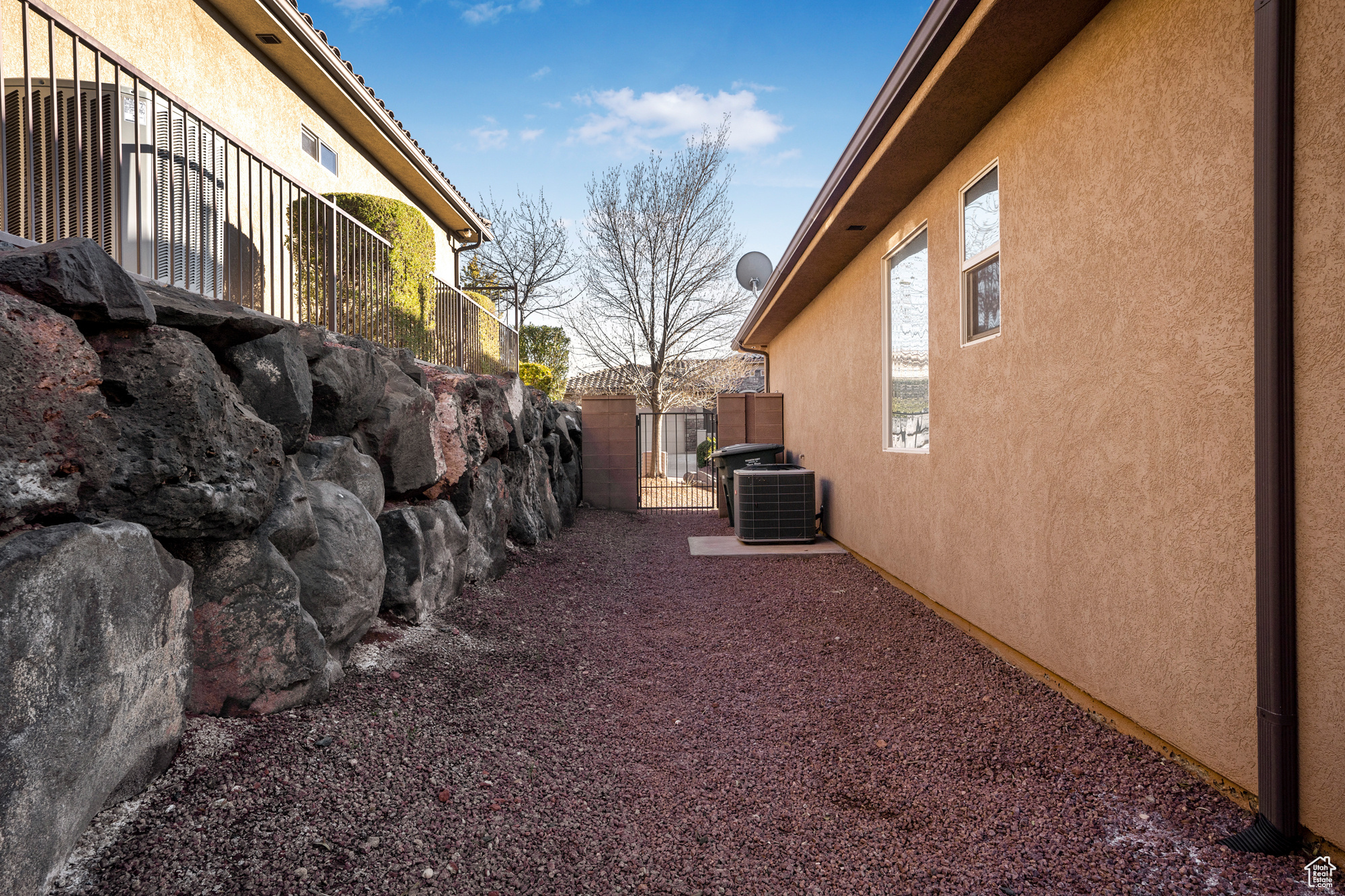 View of property exterior with central AC, fence, and stucco siding