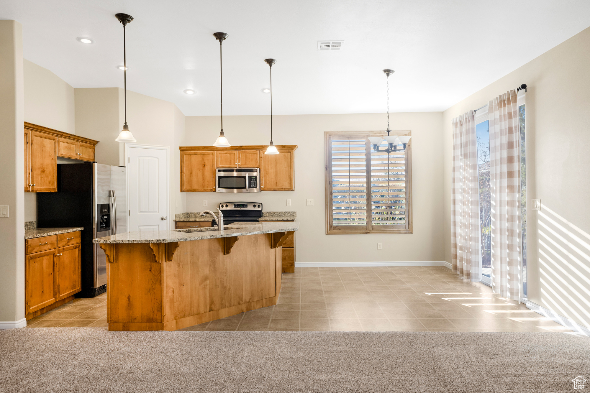 Kitchen featuring visible vents, a center island with sink, appliances with stainless steel finishes, and light colored carpet
