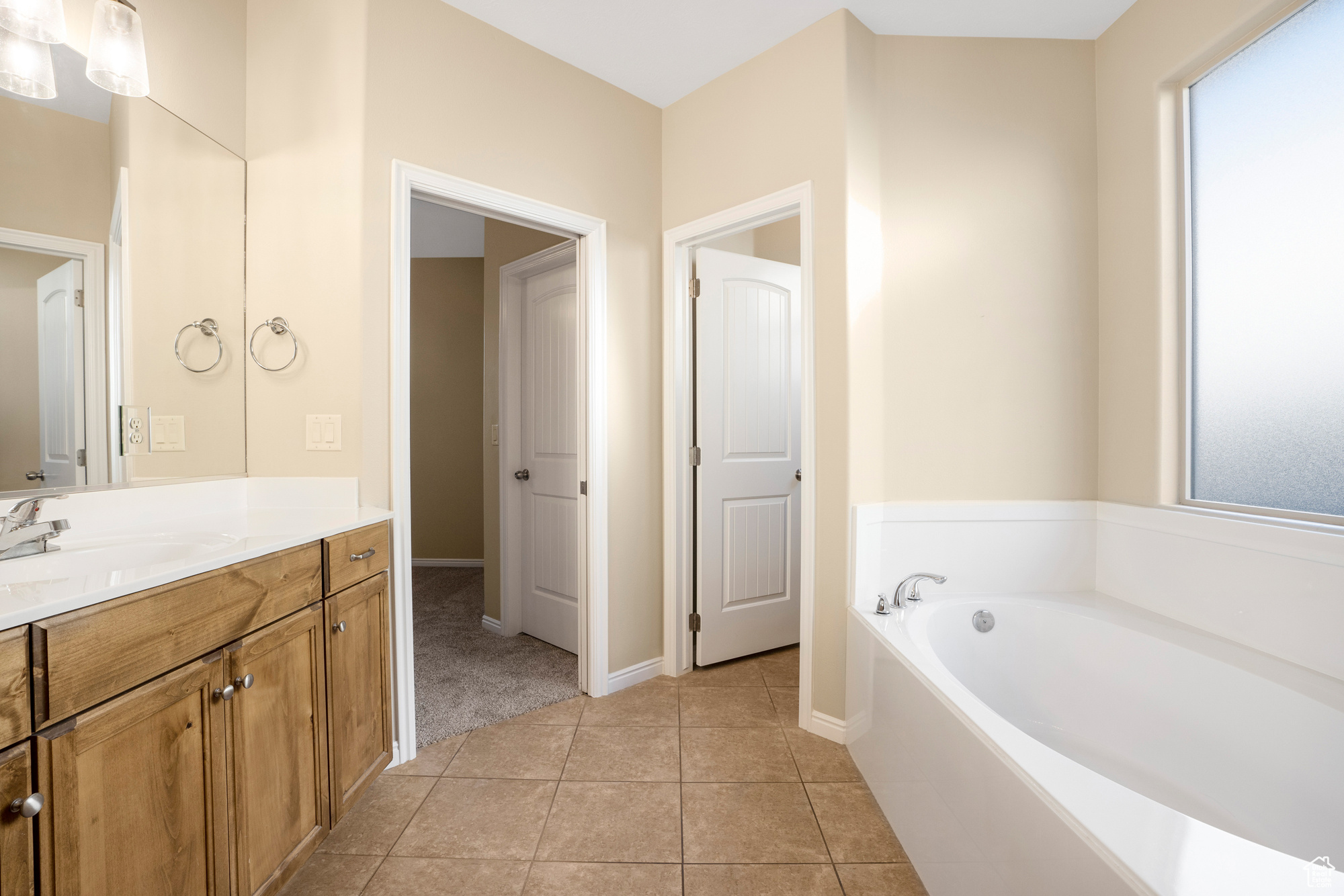 Bathroom with a bath, tile patterned flooring, vanity, and baseboards