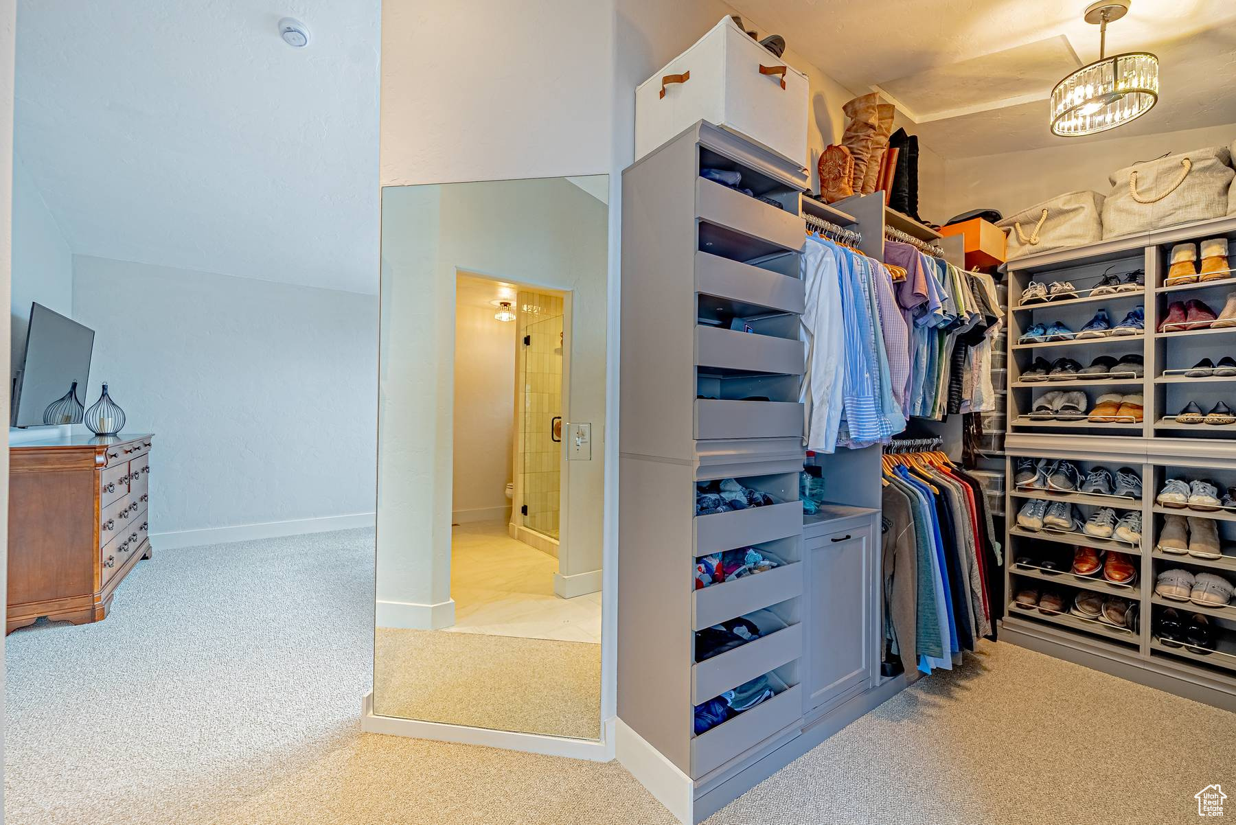 Spacious closet with an inviting chandelier and light colored carpet