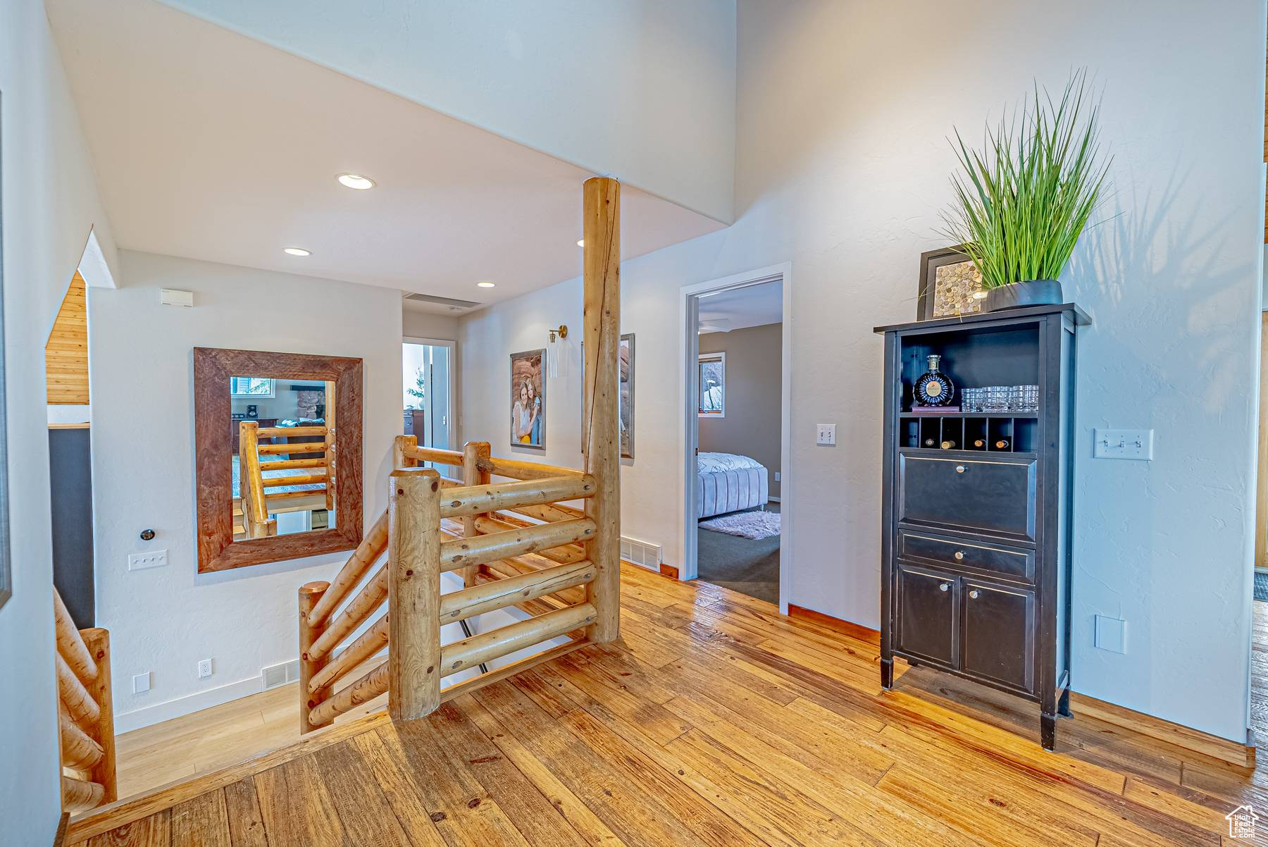 Hallway featuring light wood finished floors, an upstairs landing, visible vents, and recessed lighting