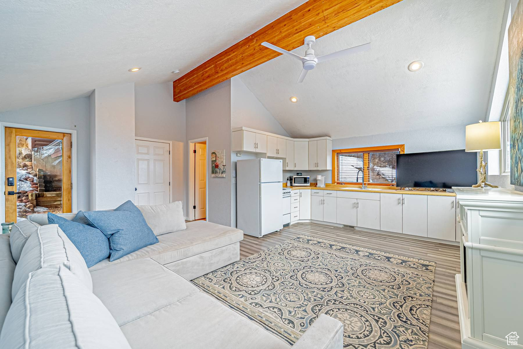 Living room with light wood-style floors, recessed lighting, vaulted ceiling with beams, and a ceiling fan