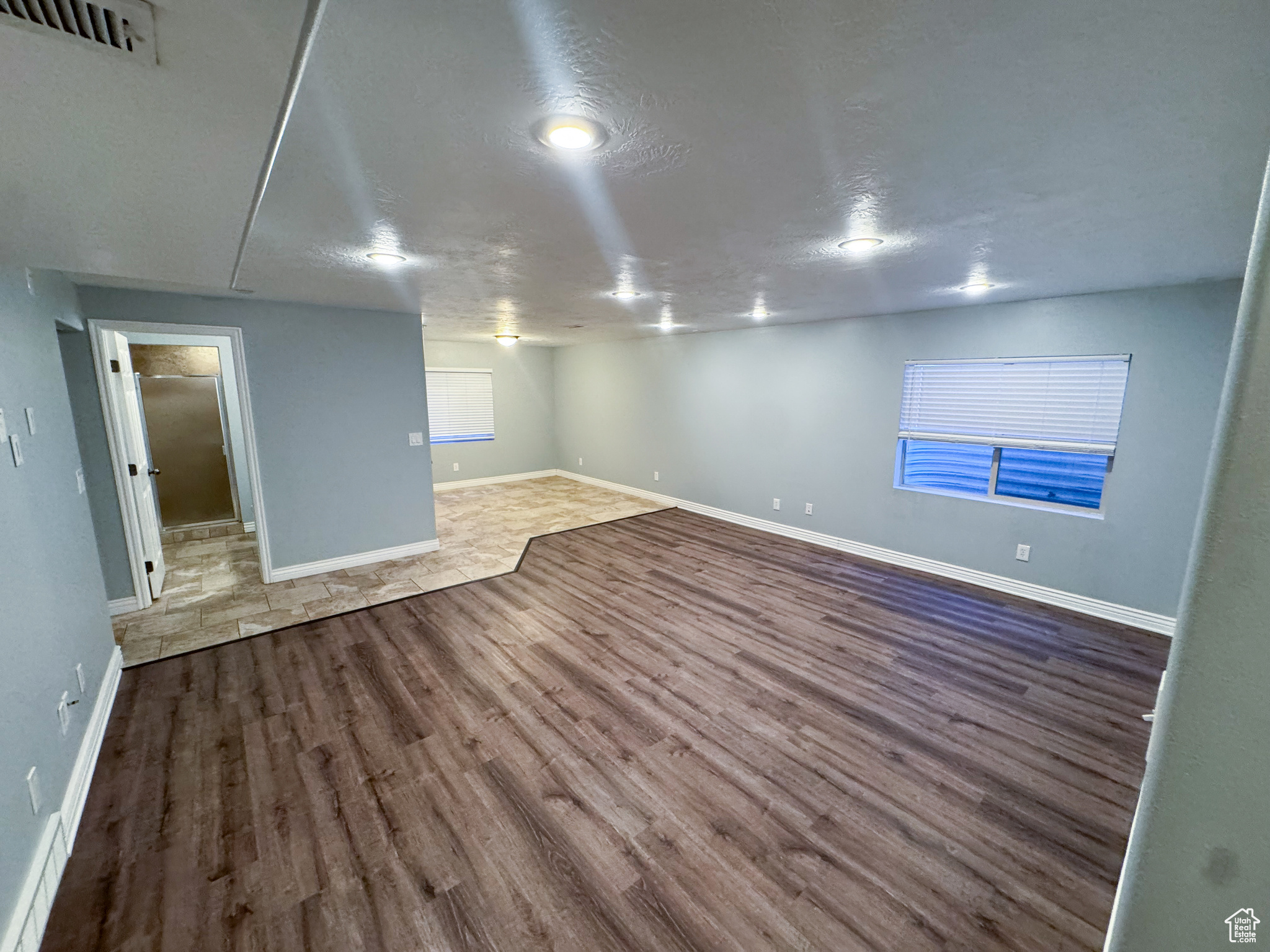 Unfurnished room featuring a textured ceiling, wood finished floors, visible vents, and baseboards