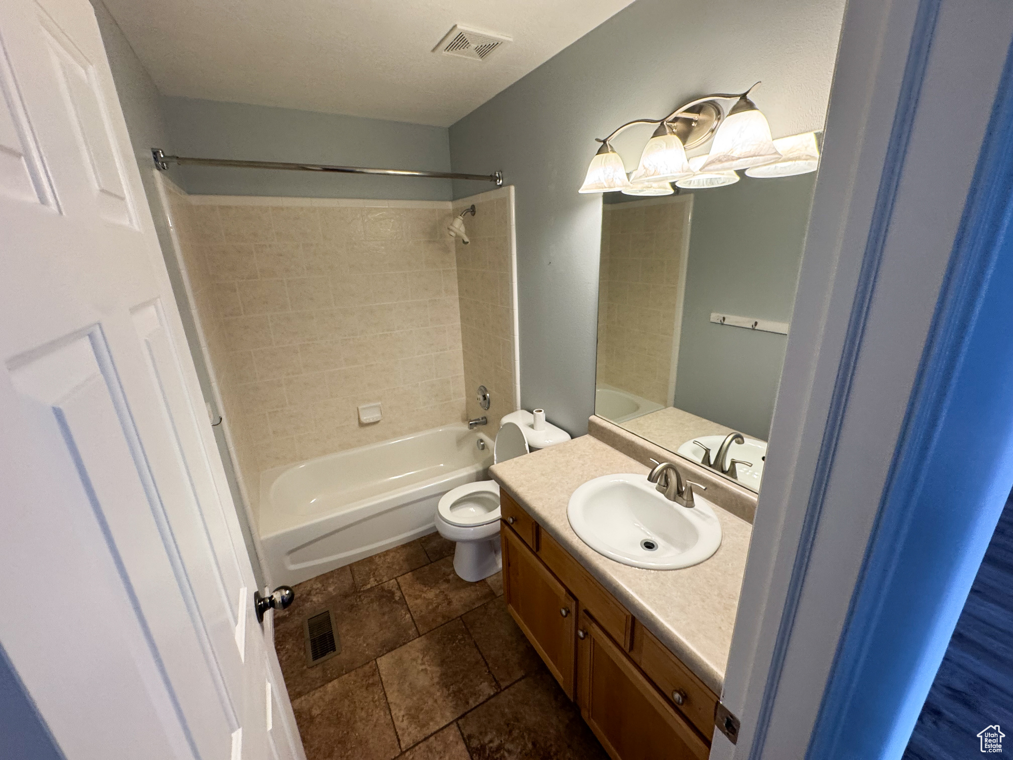 Full bathroom featuring washtub / shower combination, toilet, vanity, and visible vents