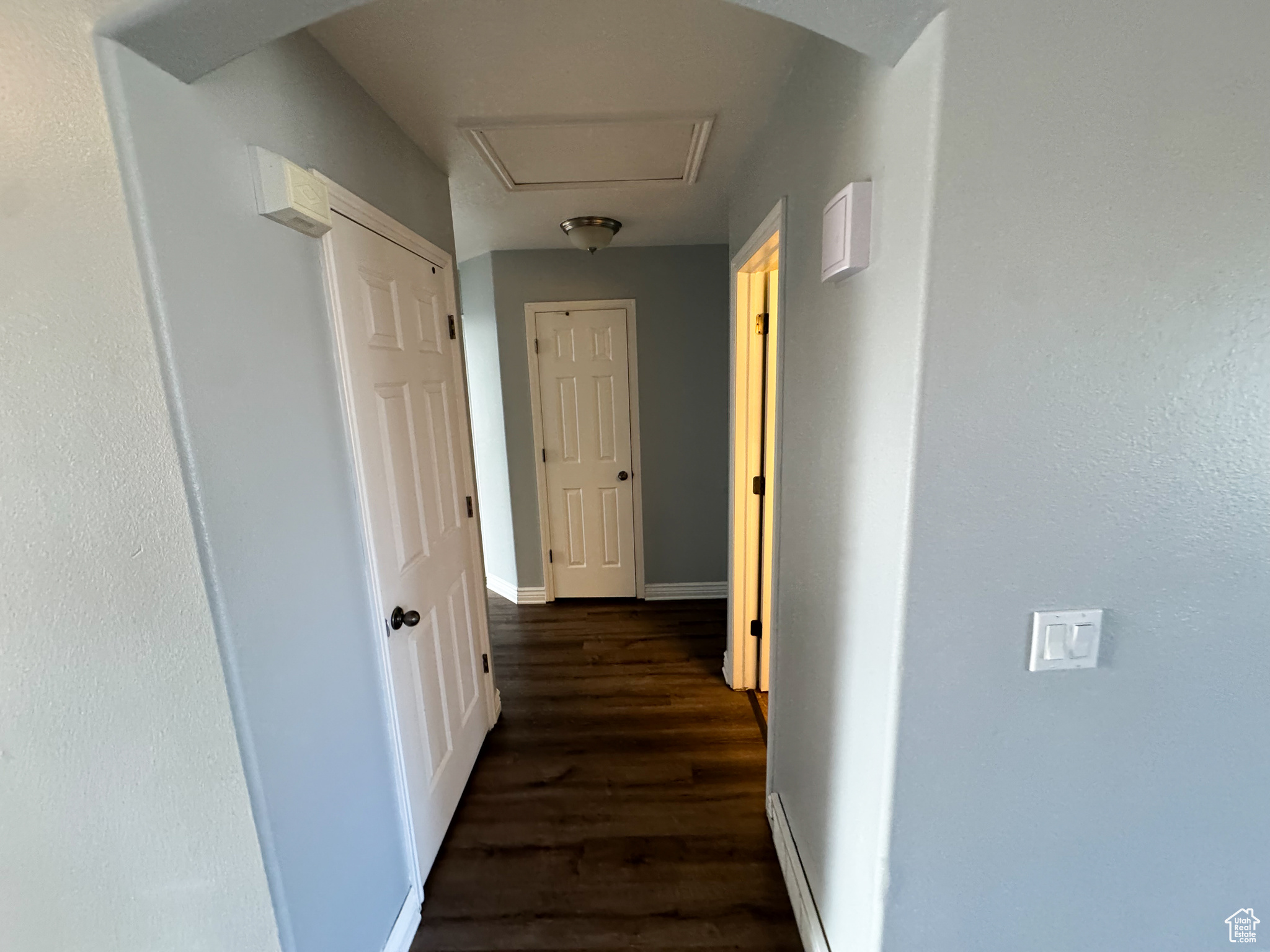 Corridor featuring baseboards and dark wood finished floors