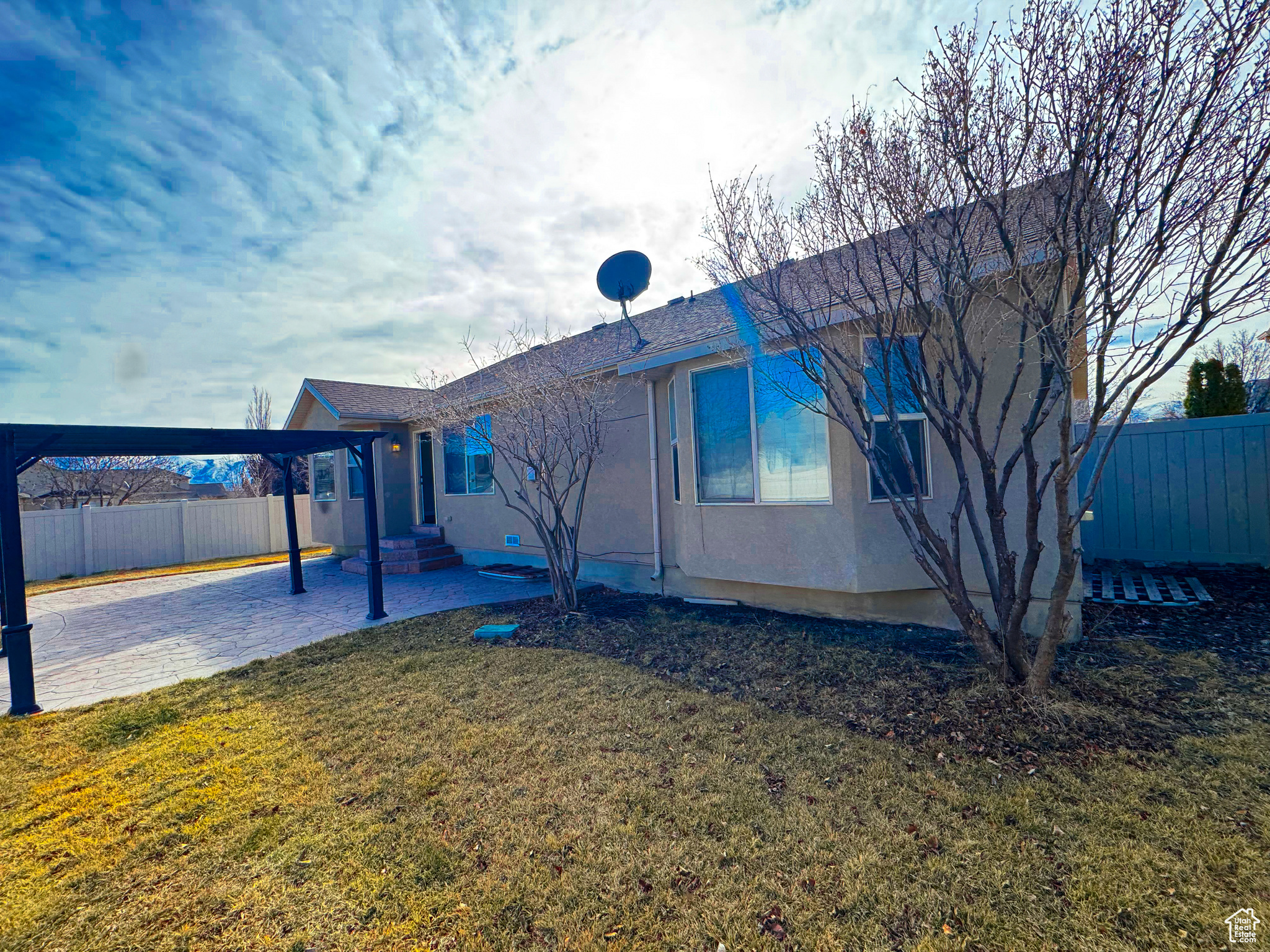 Rear view of property with a patio, a lawn, fence, and stucco siding