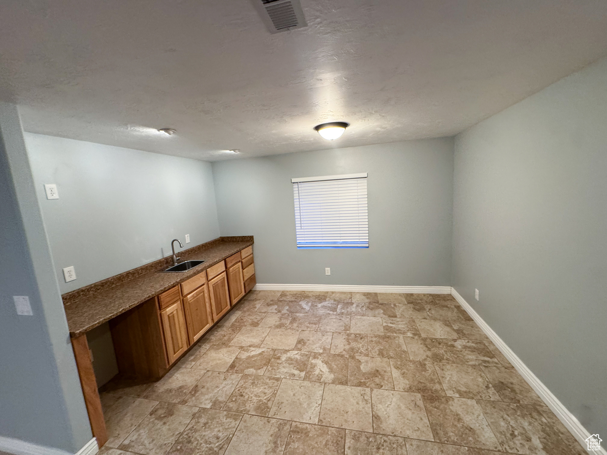 Interior space featuring stone finish floor, a sink, visible vents, and baseboards