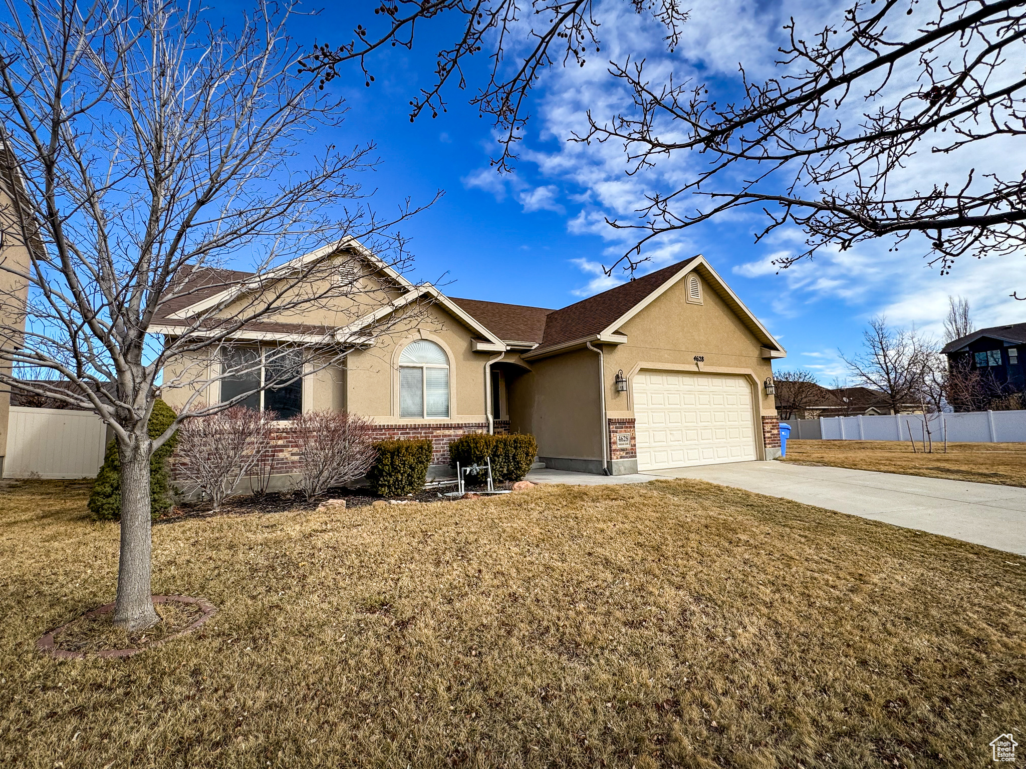 Ranch-style house featuring driveway, a front yard, and fence
