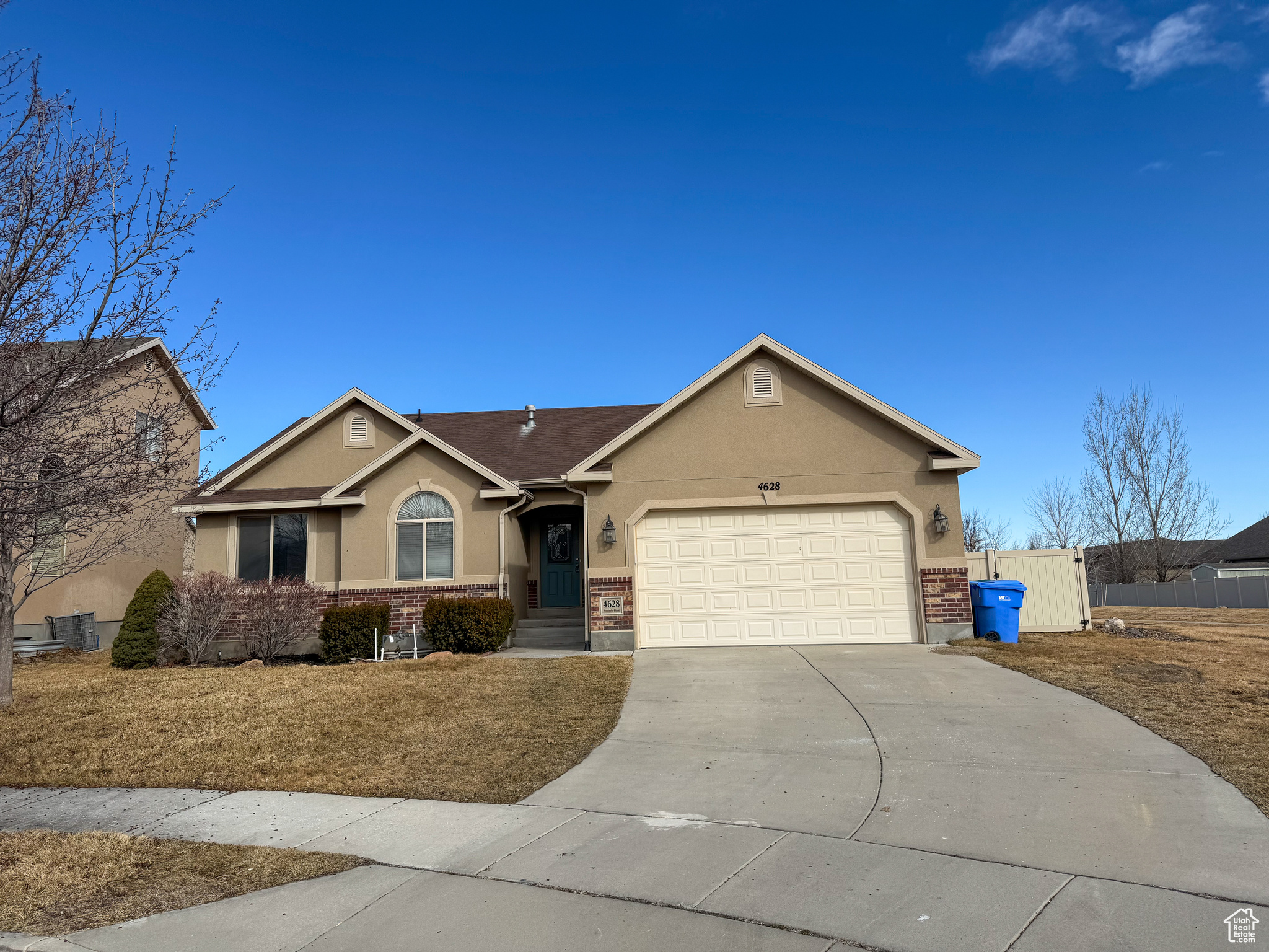 Single story home with a garage, concrete driveway, brick siding, and stucco siding