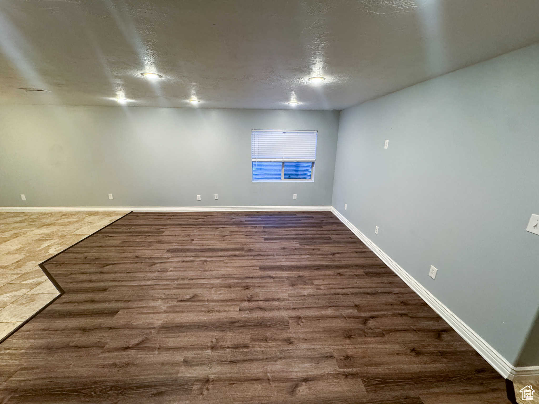 Spare room featuring a textured ceiling, baseboards, and wood finished floors