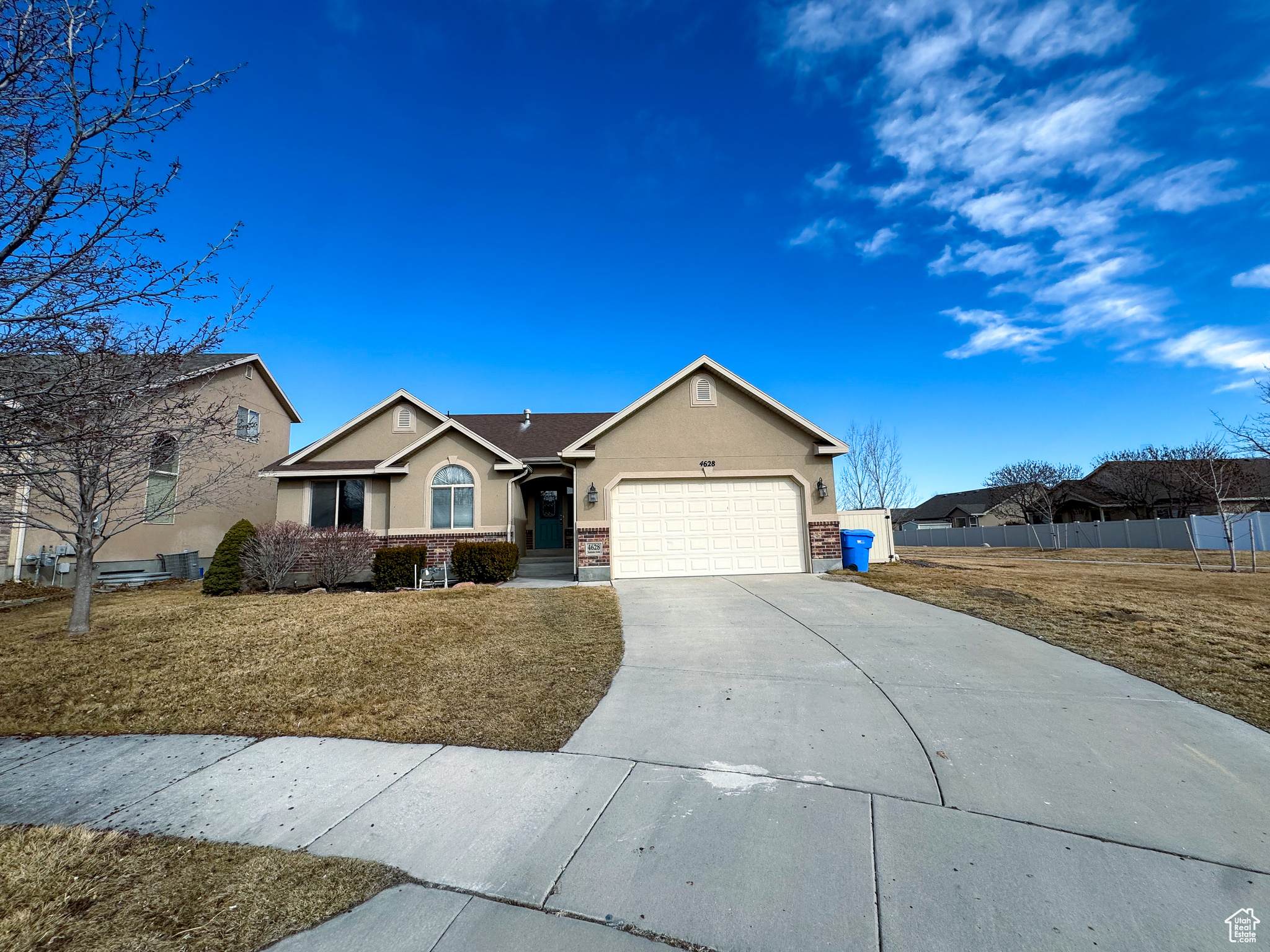Ranch-style home featuring stucco siding, concrete driveway, a front yard, fence, and a garage