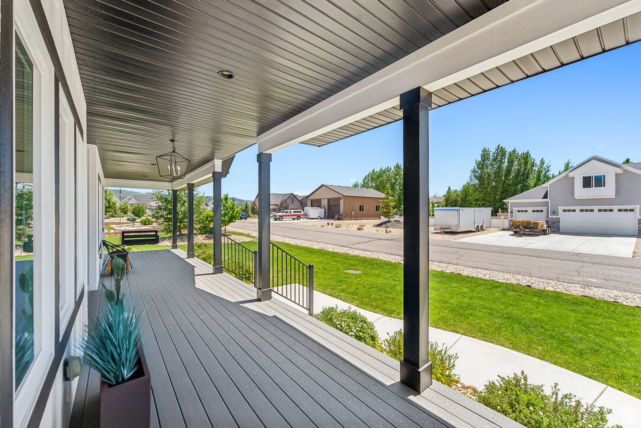 Wooden deck featuring covered porch, a lawn, and a residential view