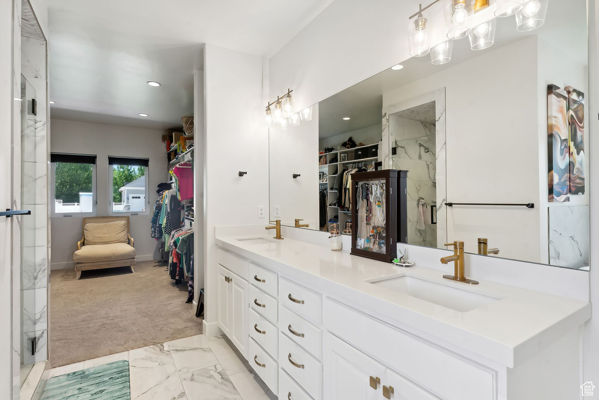 Bathroom with double vanity, a marble finish shower, a walk in closet, and a sink