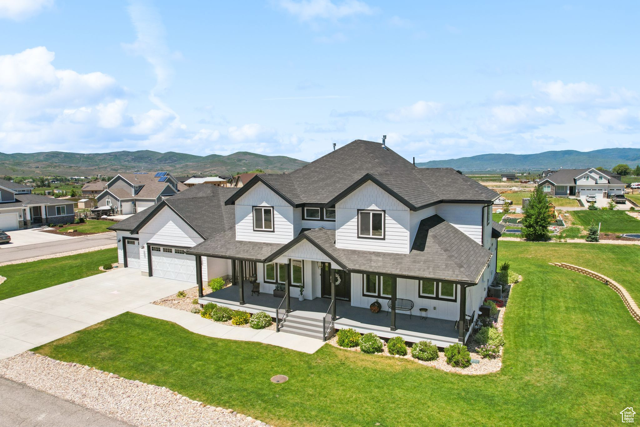 View of front facade with an attached garage, a mountain view, covered porch, roof with shingles, and a residential view