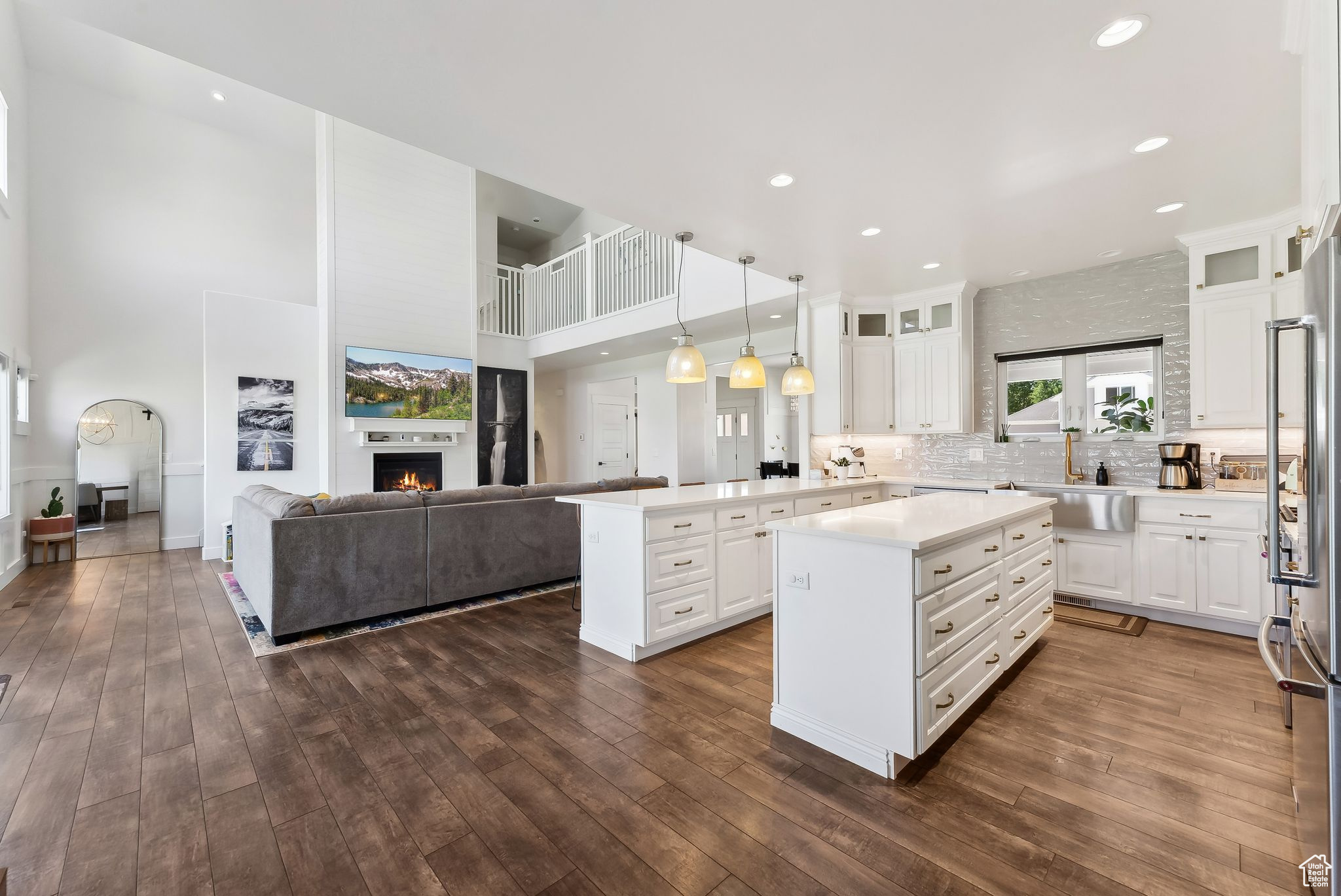 Kitchen with white cabinets, a kitchen island, glass insert cabinets, hanging light fixtures, and light countertops