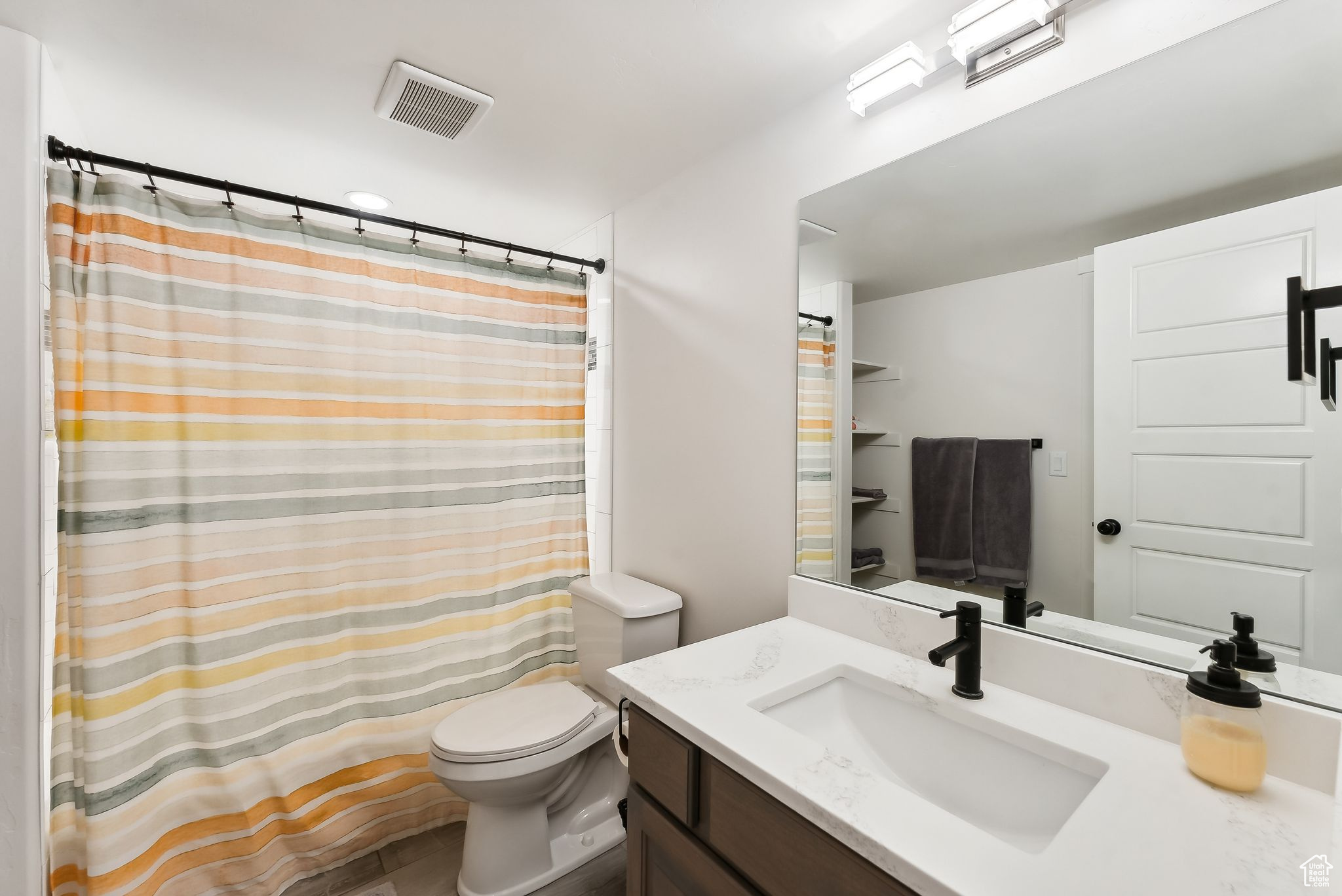 Bathroom with toilet, visible vents, and vanity