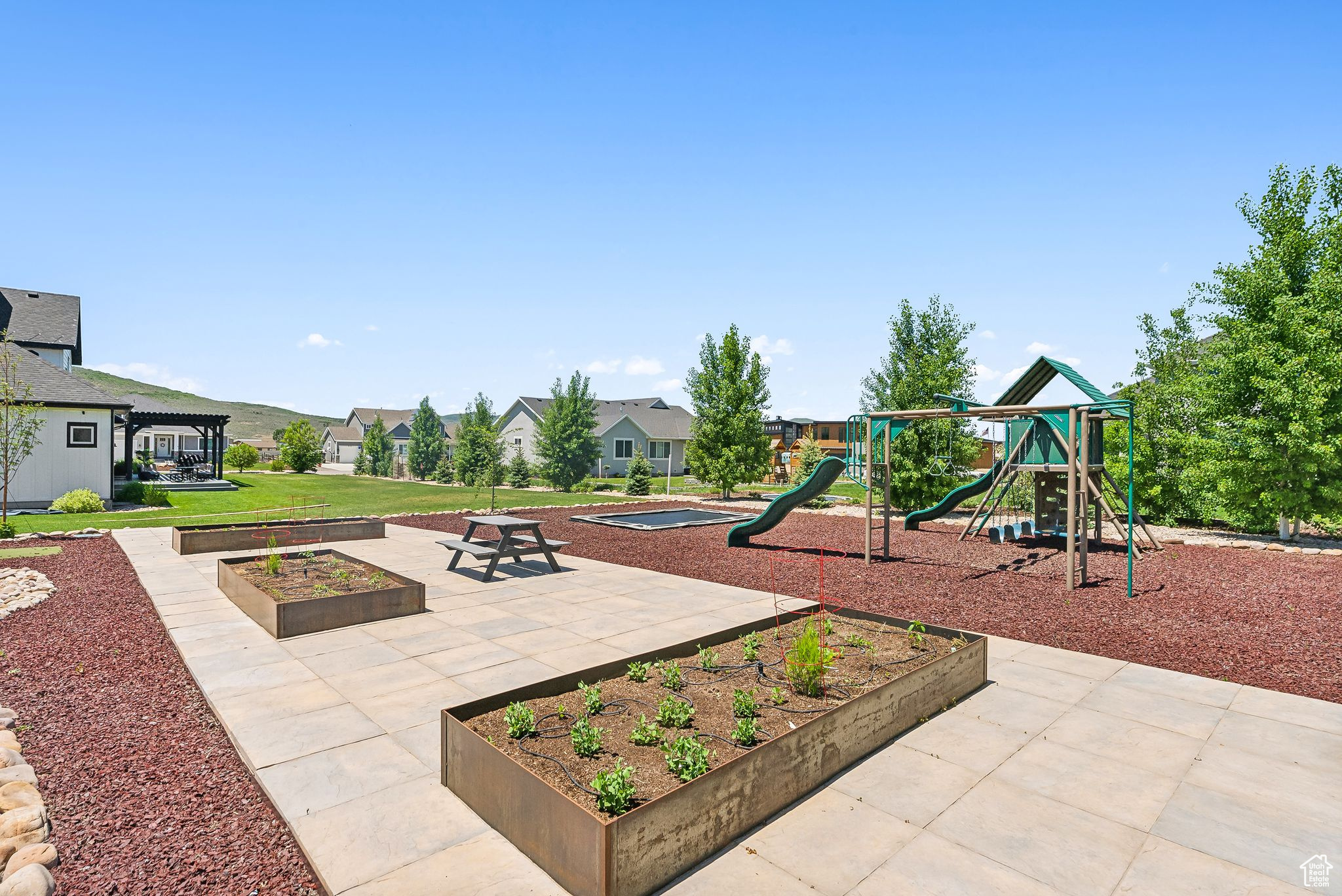 Communal playground with a patio area, a residential view, and a lawn