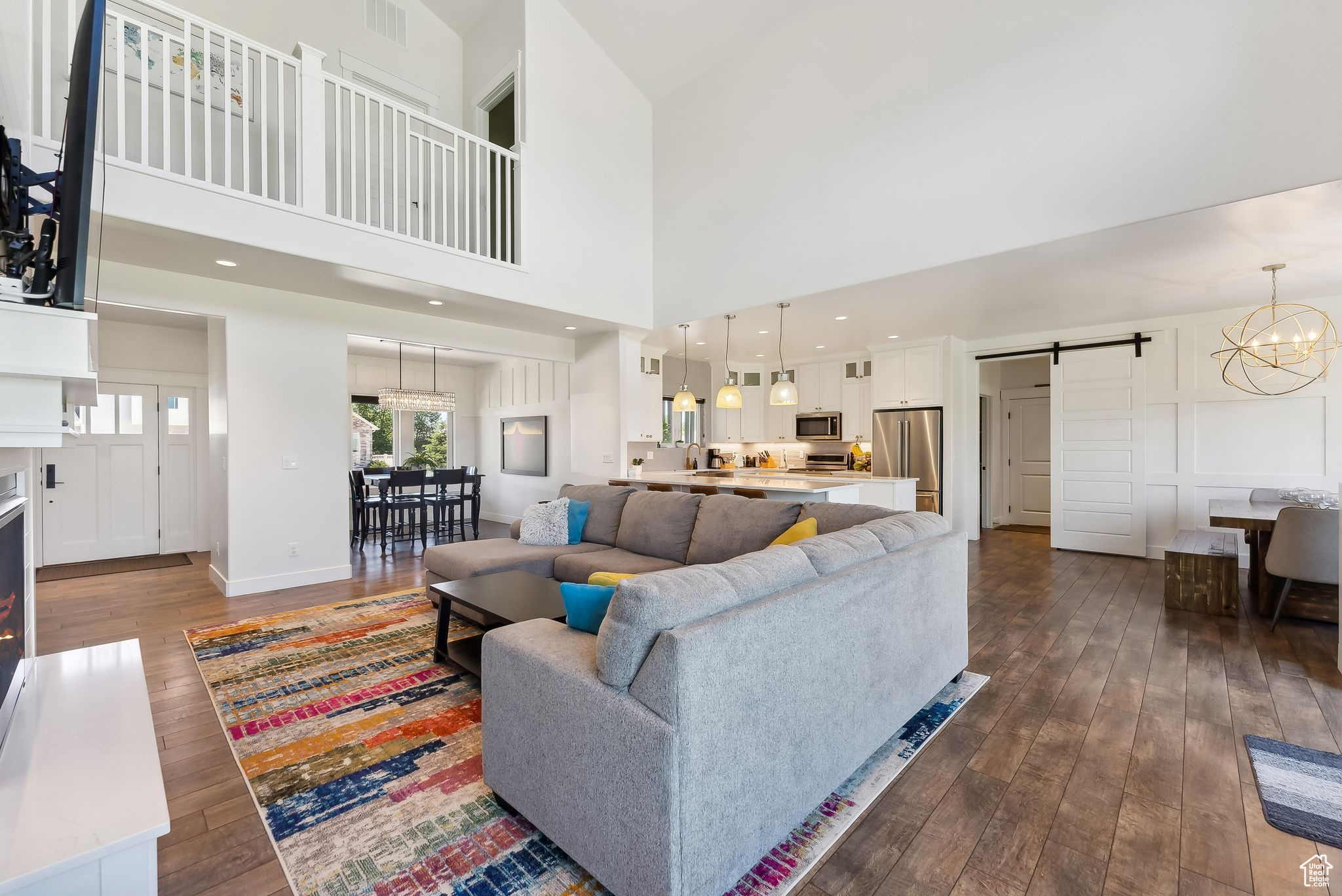 Living area featuring a barn door, visible vents, a towering ceiling, dark wood-style flooring, and a chandelier