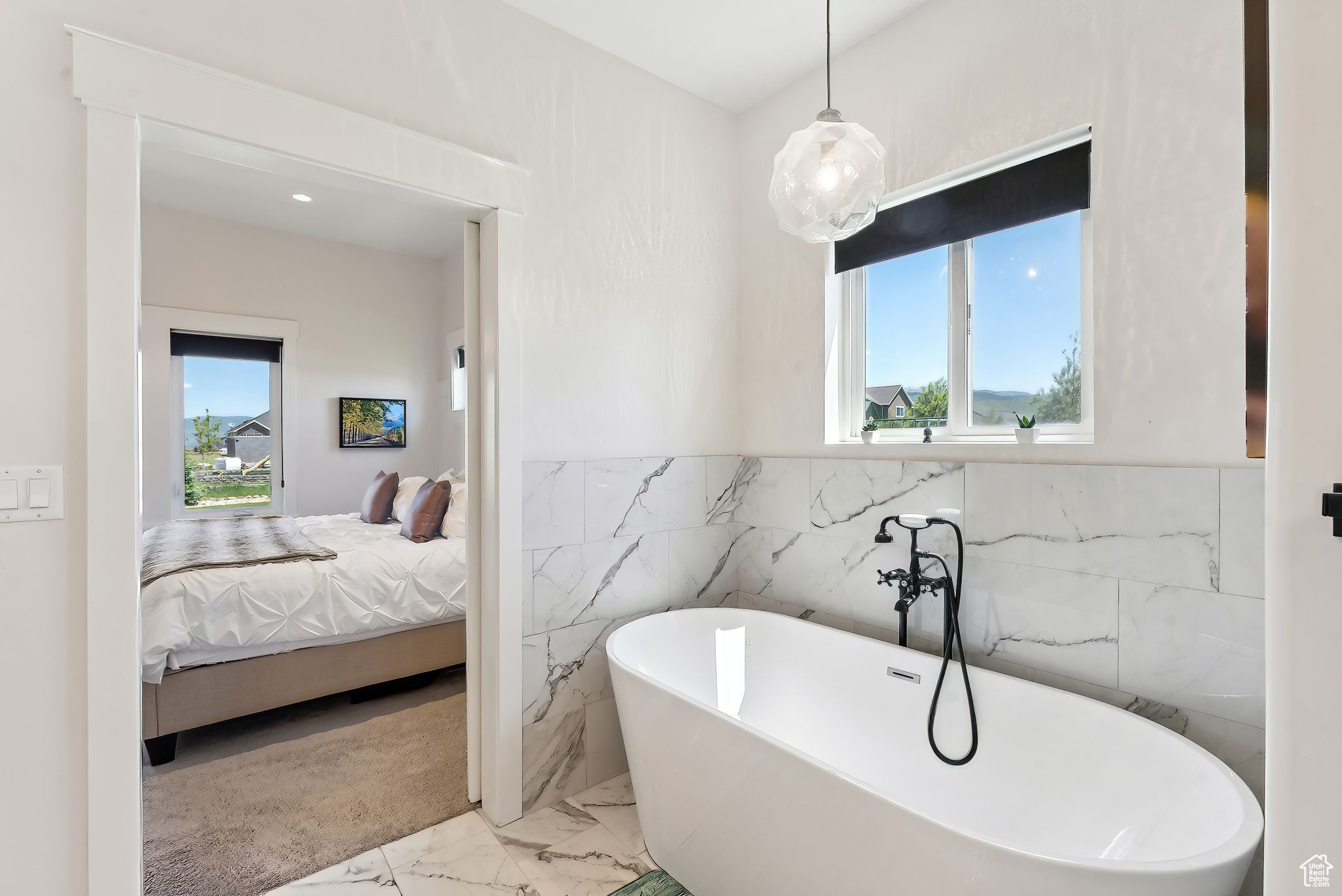 Bathroom featuring marble finish floor, tile walls, wainscoting, connected bathroom, and a freestanding tub