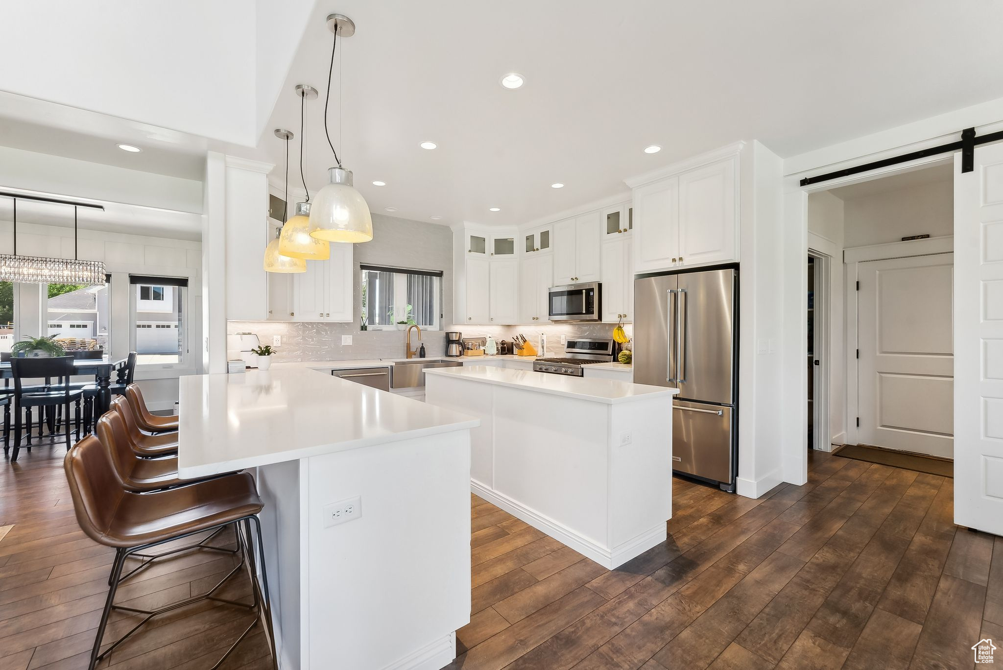 Kitchen with a barn door, stainless steel appliances, a kitchen island, hanging light fixtures, and light countertops