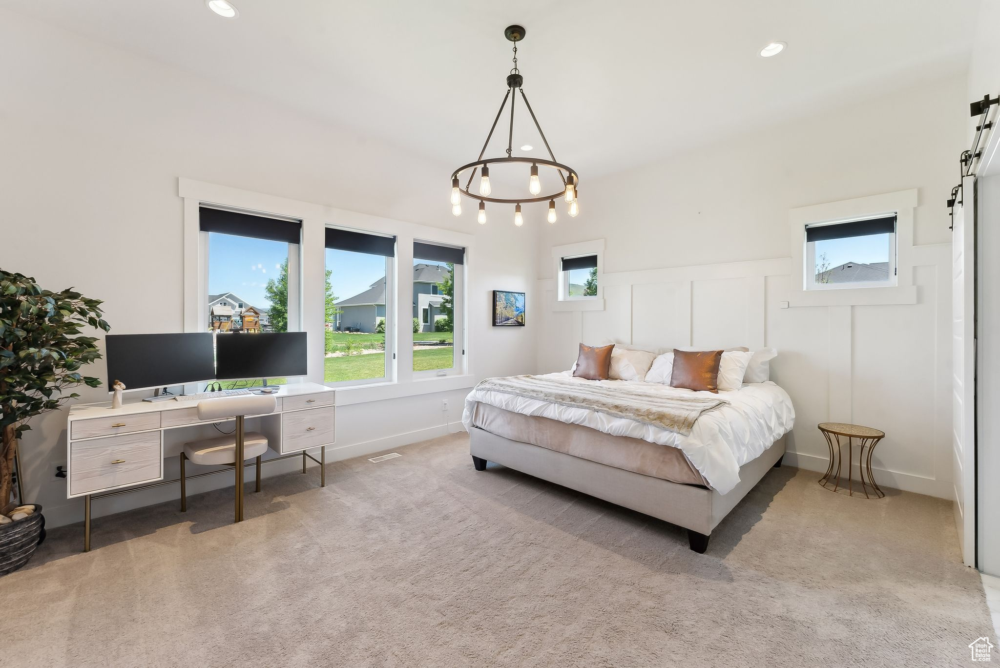 Bedroom featuring a barn door, light colored carpet, a wainscoted wall, a decorative wall, and recessed lighting
