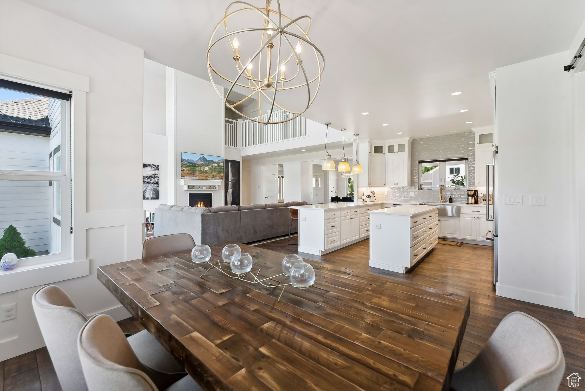 Dining area featuring dark wood-type flooring, recessed lighting, a warm lit fireplace, and a chandelier