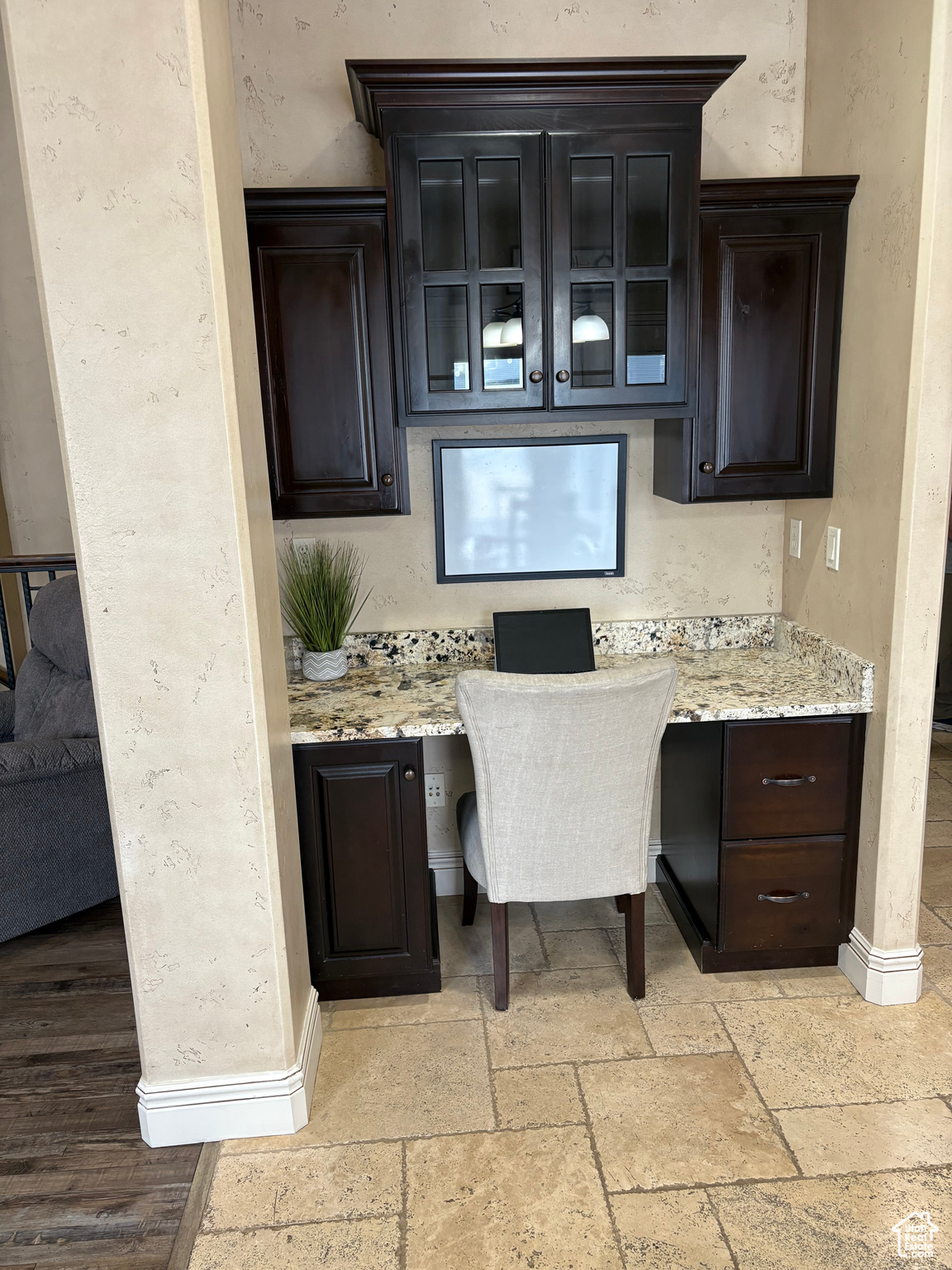 Interior space featuring stone tile flooring, built in study area, and baseboards