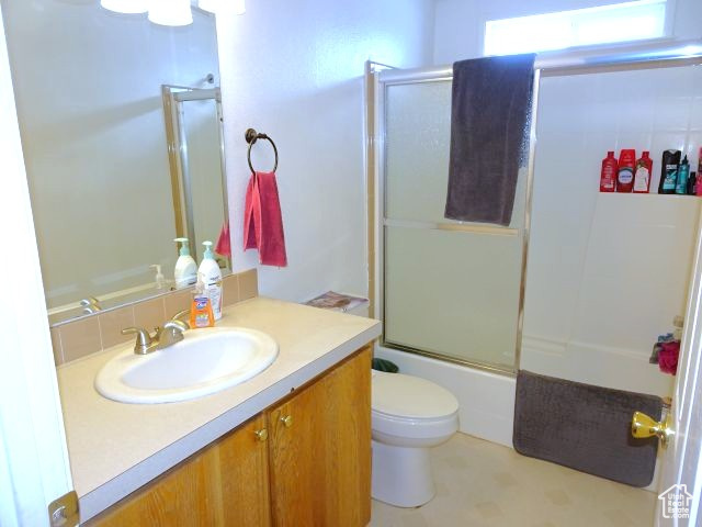 Bathroom with toilet, combined bath / shower with glass door, and vanity