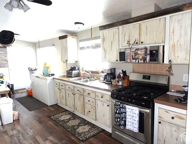 Kitchen featuring dark wood-style floors, ceiling fan, stainless steel range with gas cooktop, and a sink