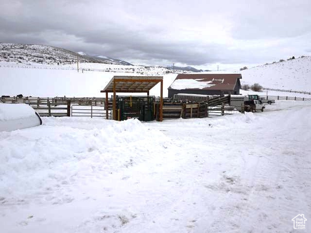 Yard covered in snow featuring fence, a mountain view, and a detached carport