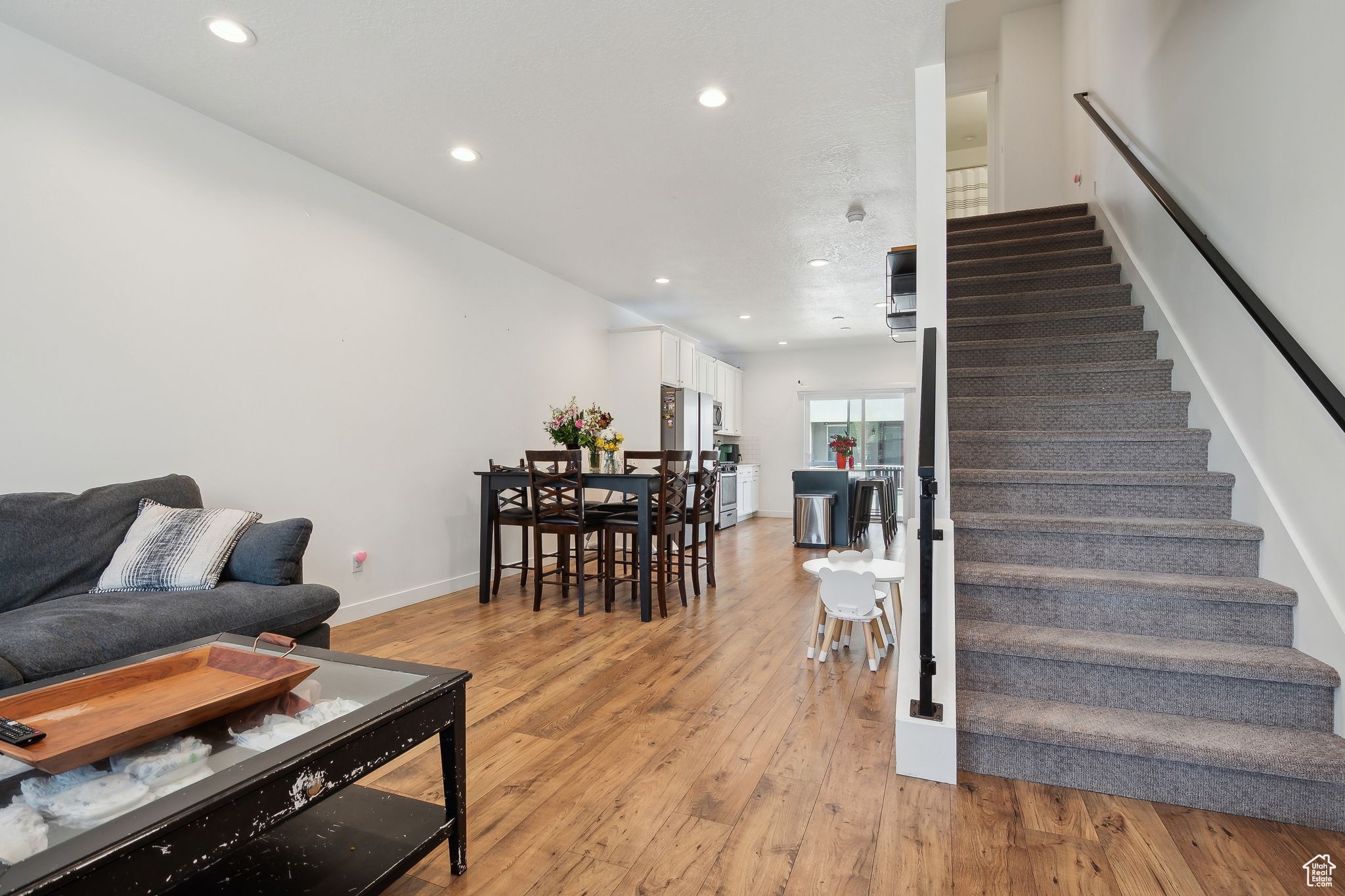 Living room with stairs, light wood-type flooring, baseboards, and recessed lighting