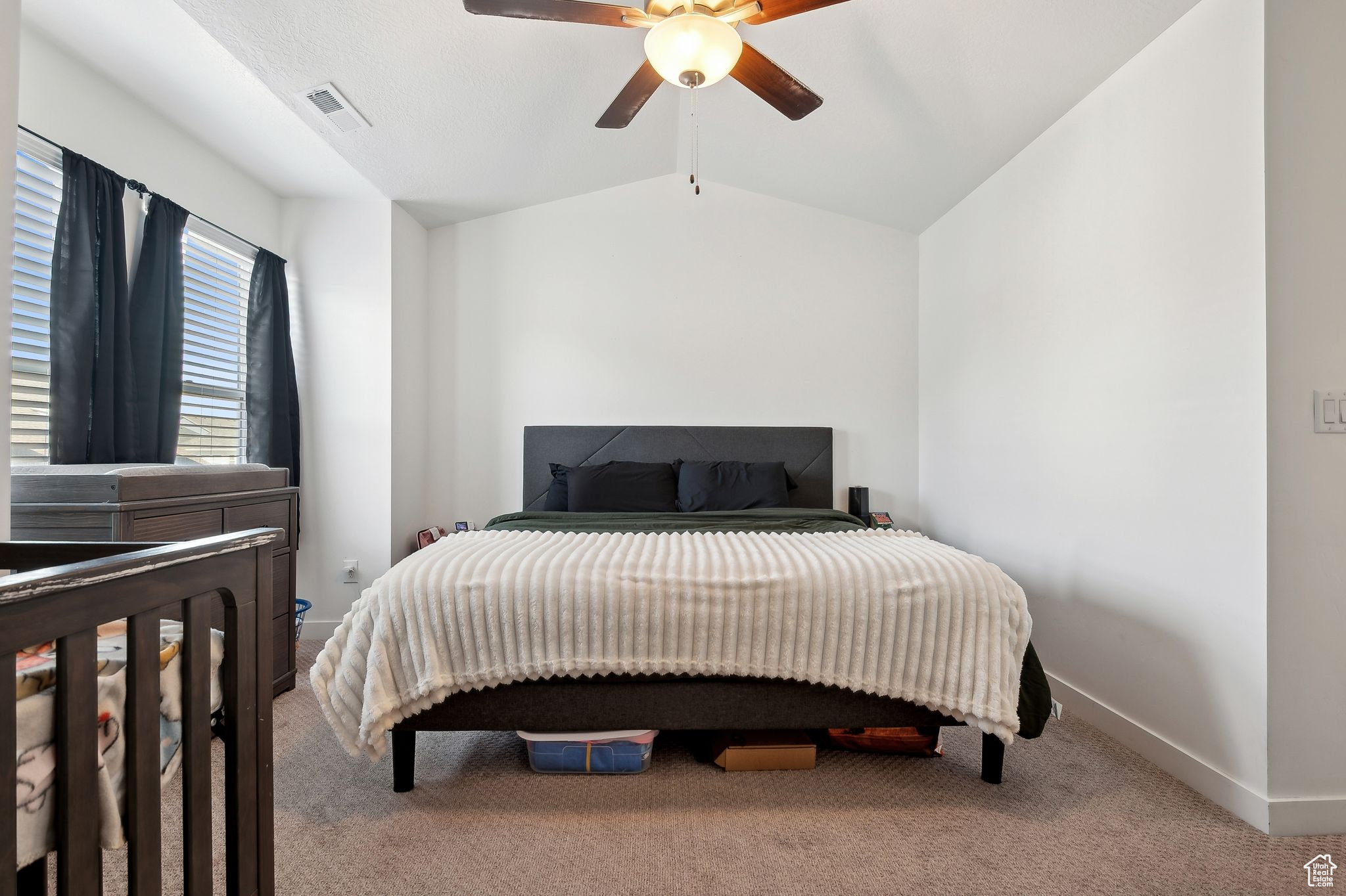 Bedroom with ceiling fan, carpet flooring, visible vents, baseboards, and vaulted ceiling