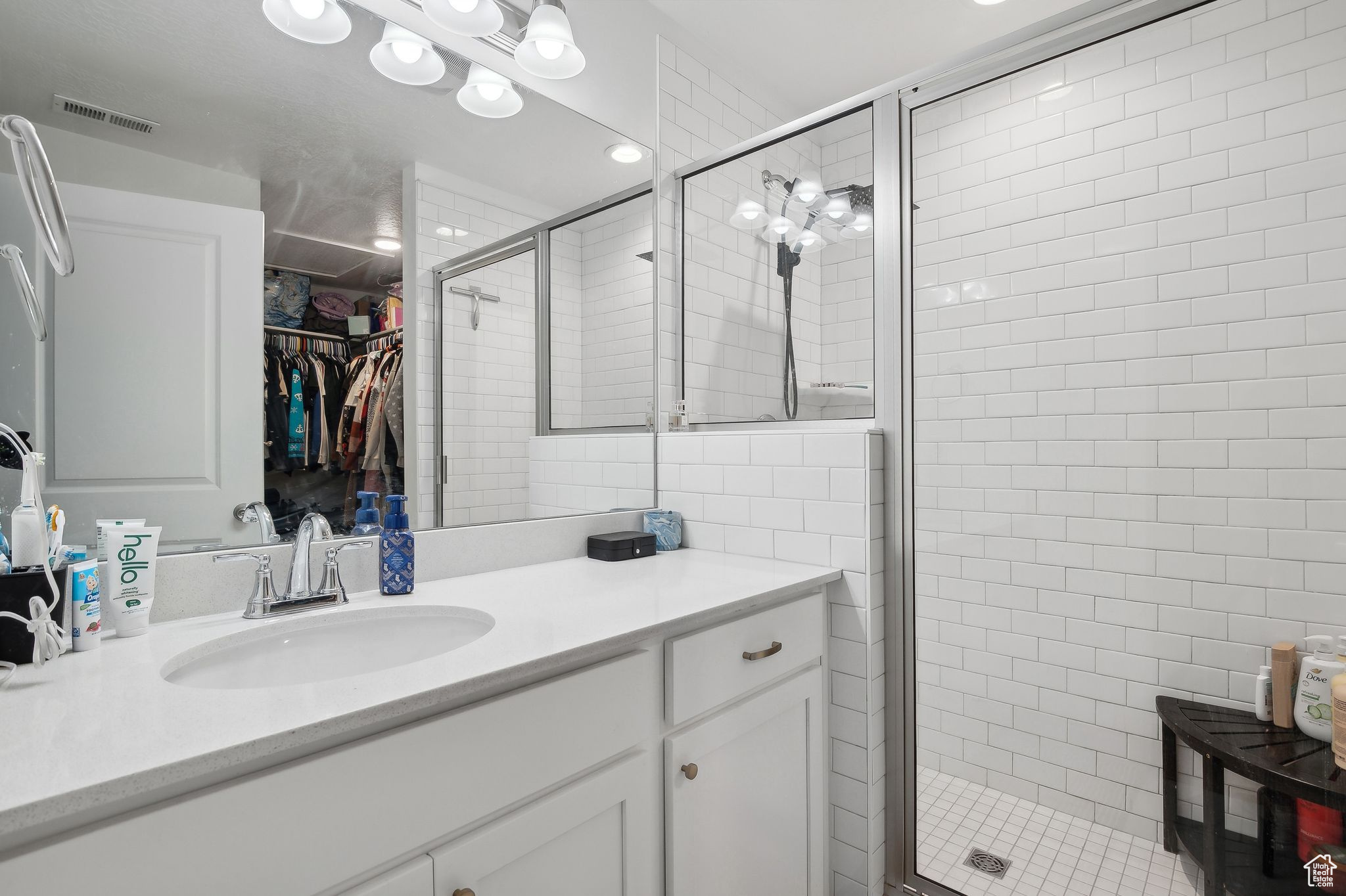 Bathroom featuring a shower stall, visible vents, a walk in closet, and vanity