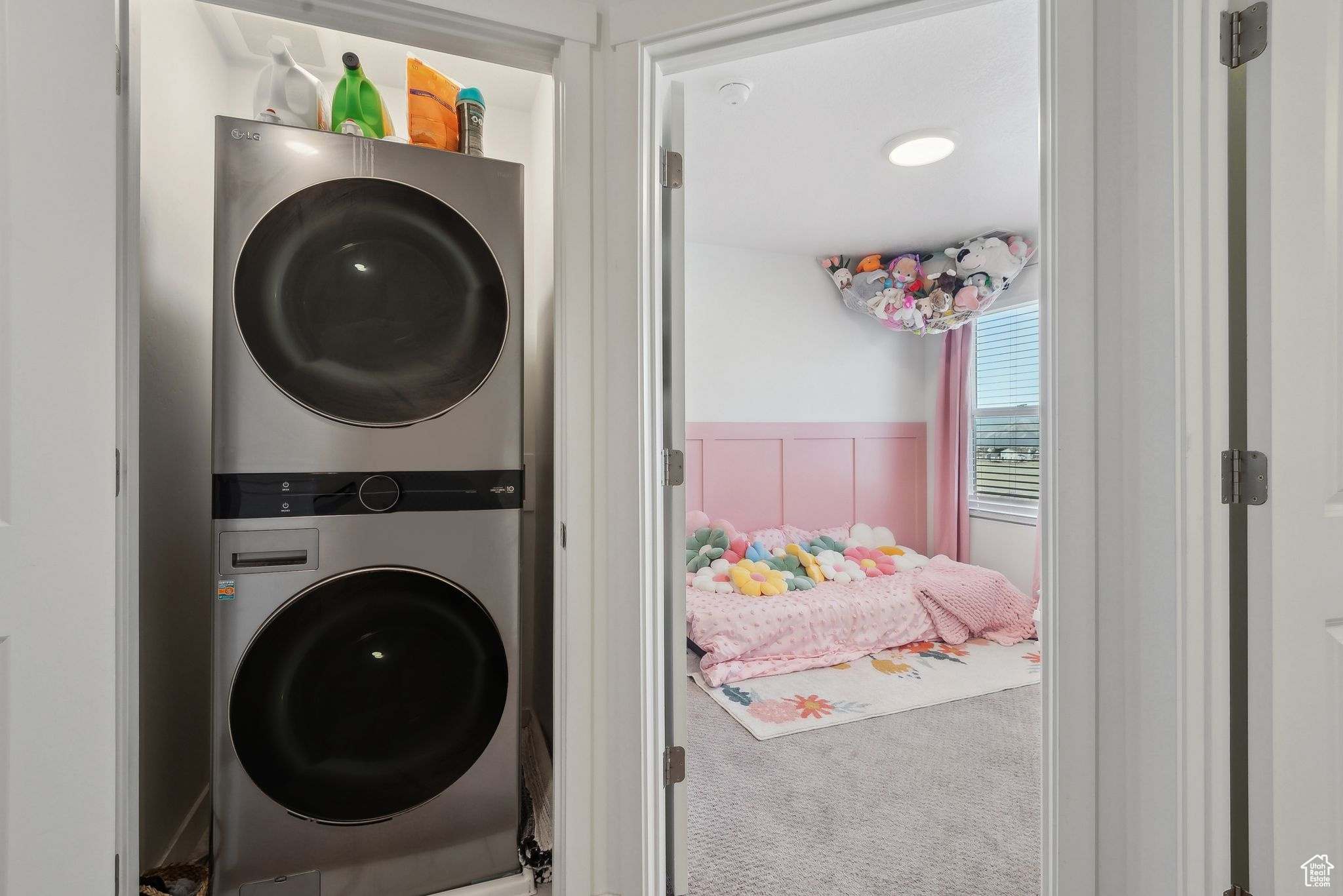 Clothes washing area with carpet, stacked washer and clothes dryer, a wainscoted wall, and laundry area