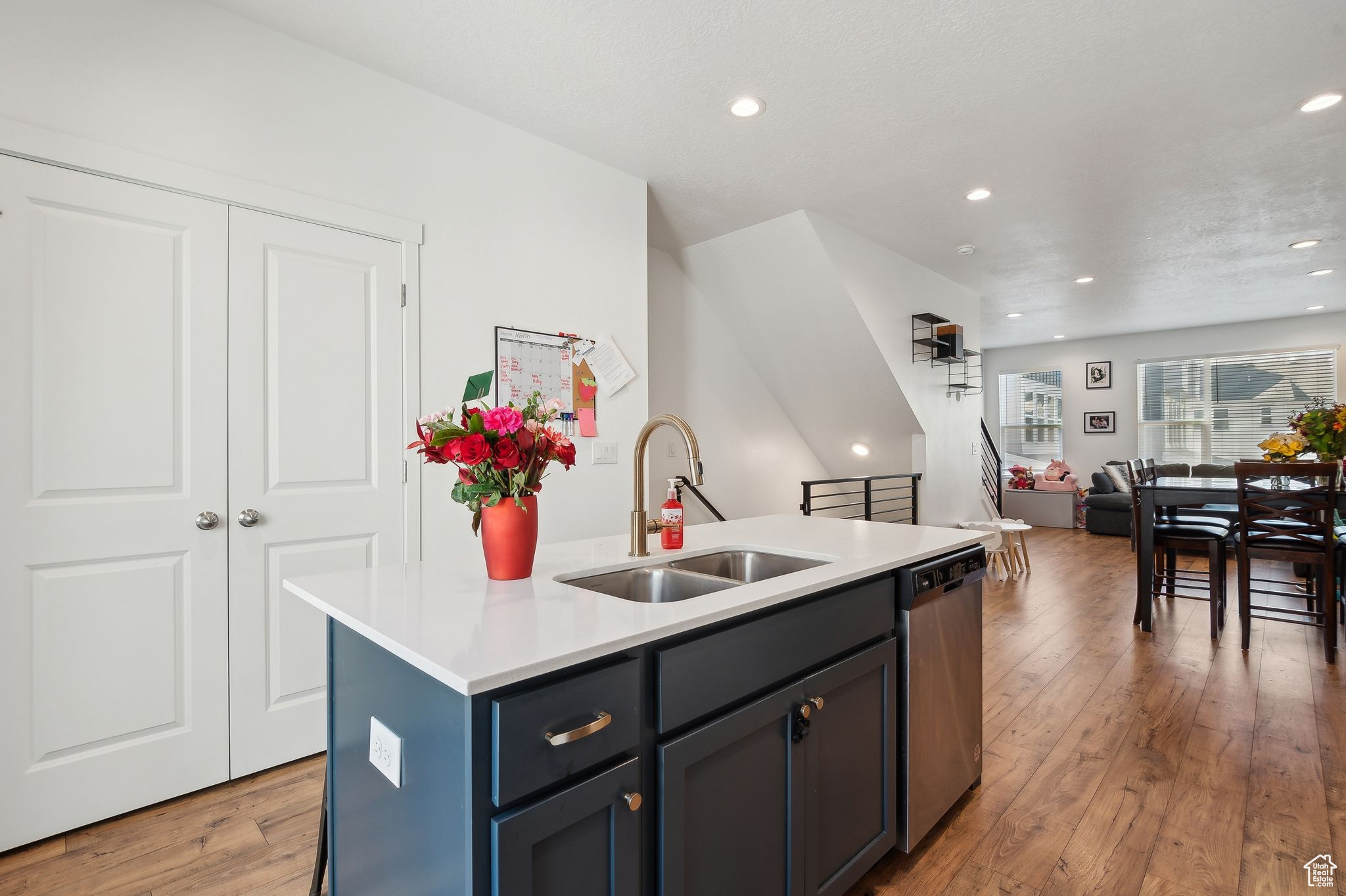 Kitchen with a center island with sink, light countertops, stainless steel dishwasher, light wood-style floors, and a sink
