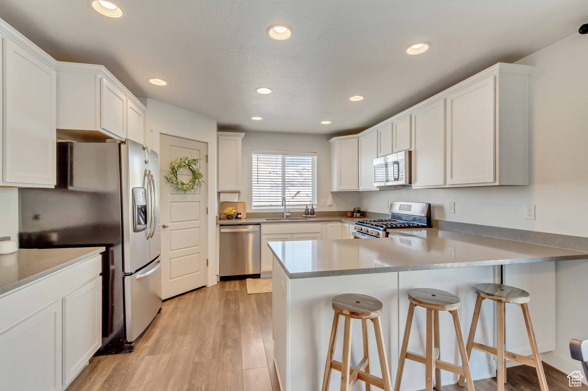 Kitchen featuring stainless steel appliances, light countertops, white cabinets, and a peninsula