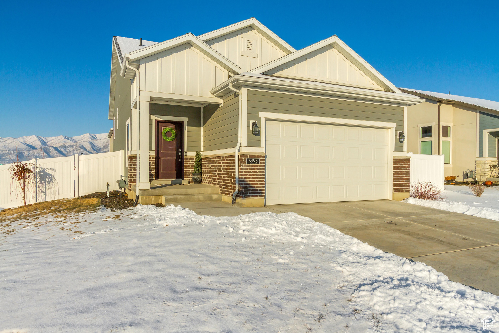 Craftsman house with an attached garage, a mountain view, brick siding, fence, and board and batten siding