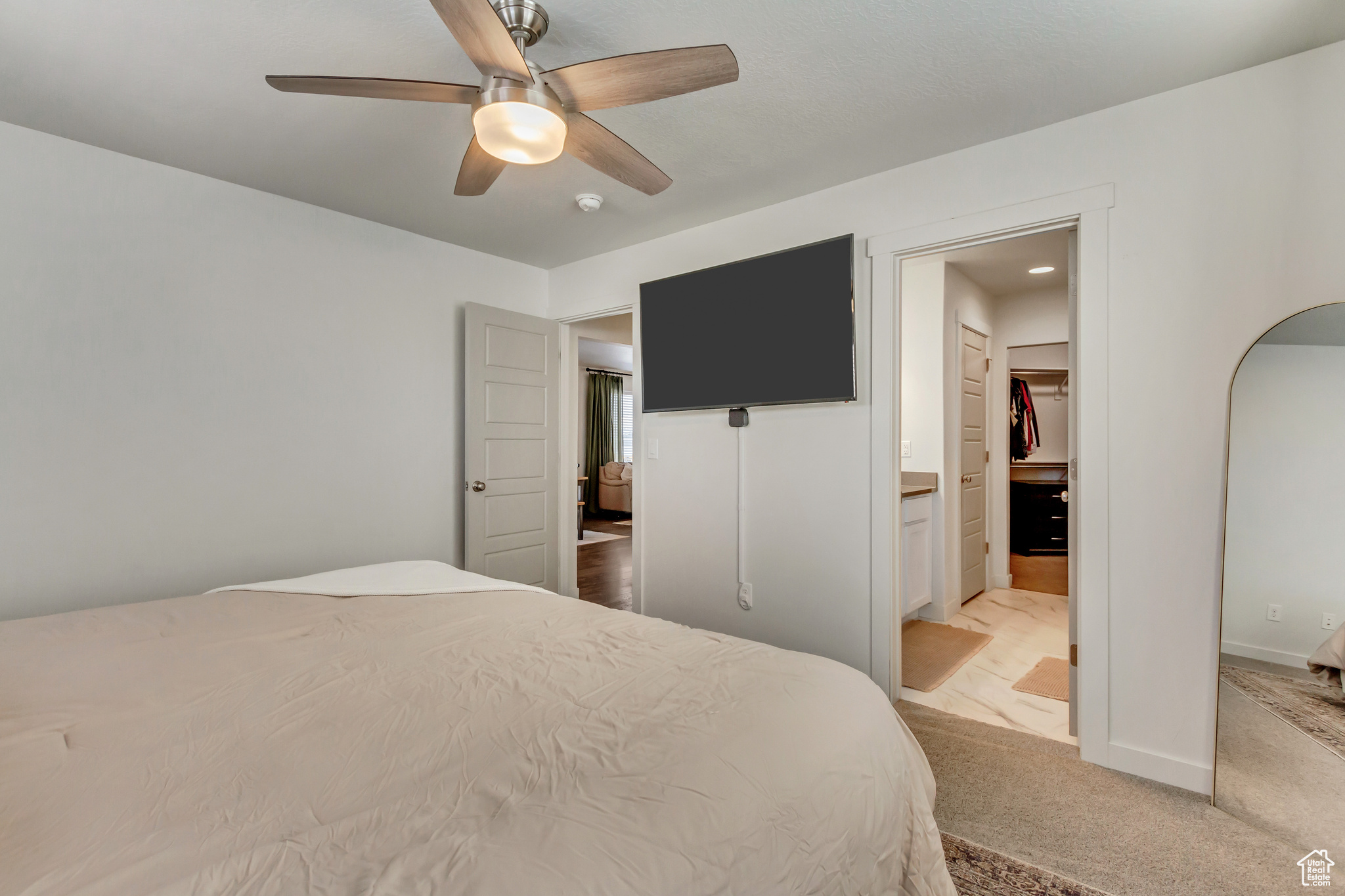 Bedroom with arched walkways, ensuite bathroom, light colored carpet, a ceiling fan, and baseboards