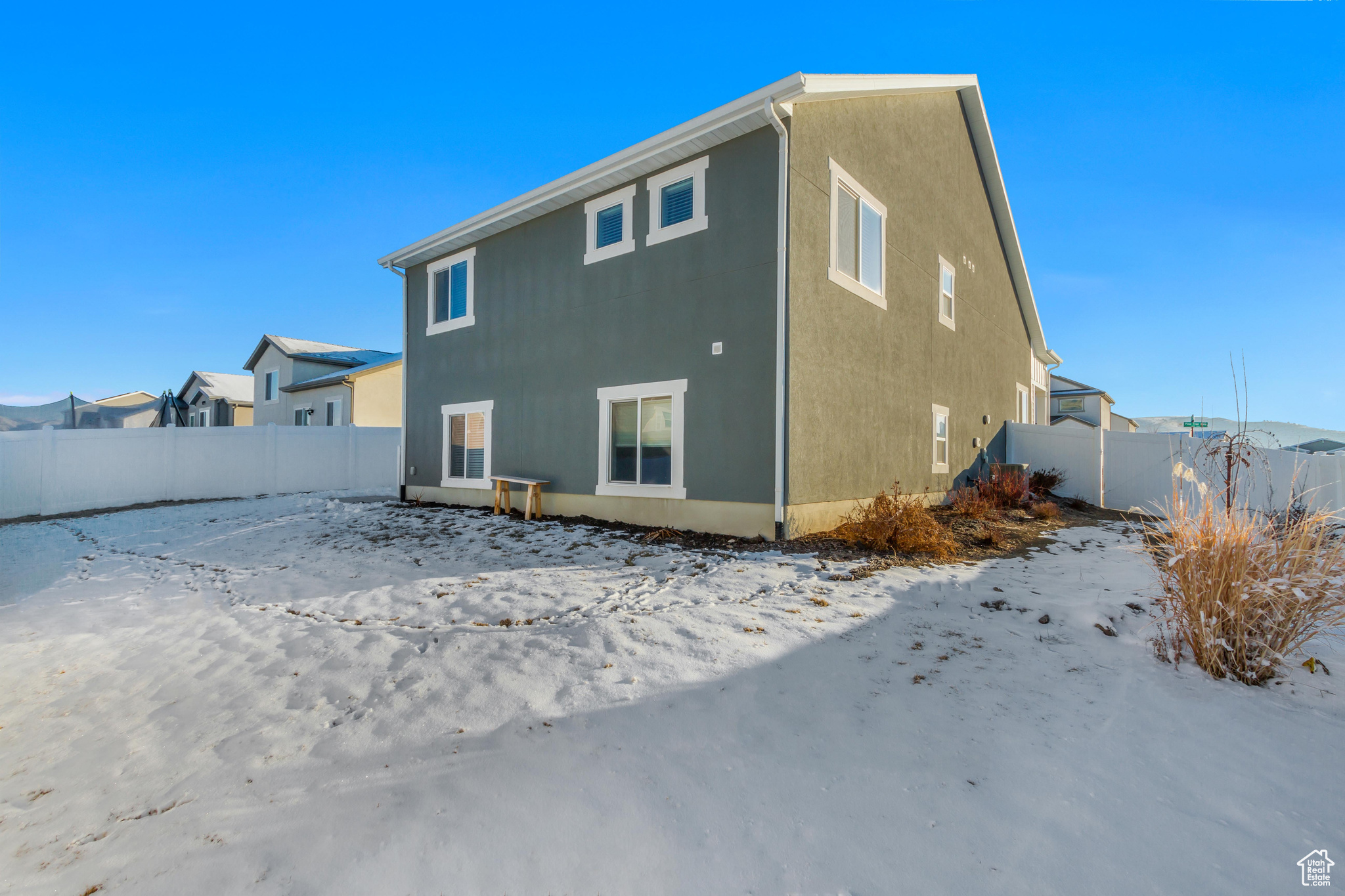 Snow covered rear of property featuring fence and stucco siding
